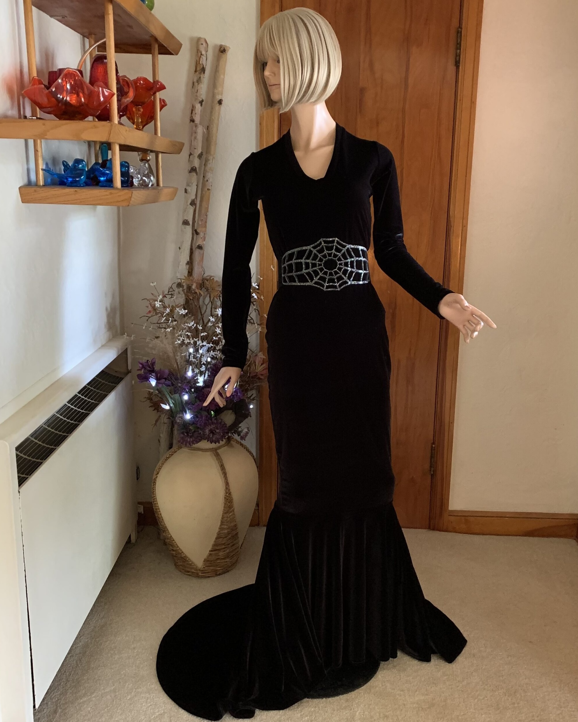 Full-length black velvet mermaid gown with long sleeves and dramatic flared train displayed on mannequin