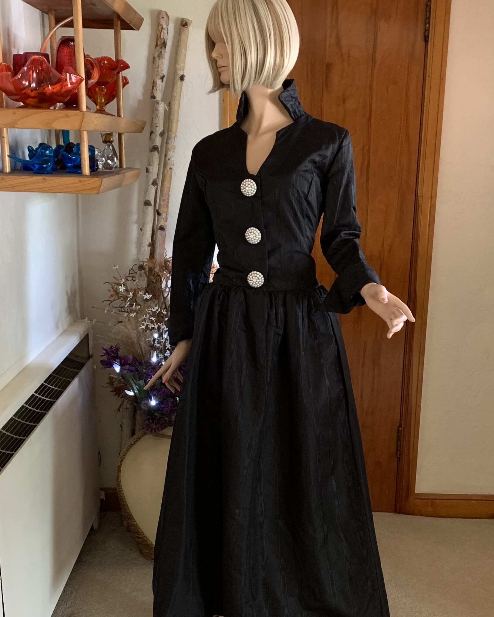 Vintage black moiré evening dress by Josephine M. Kahn displayed on mannequin with sculptural high collar, pearl buttons, and full gathered skirt.