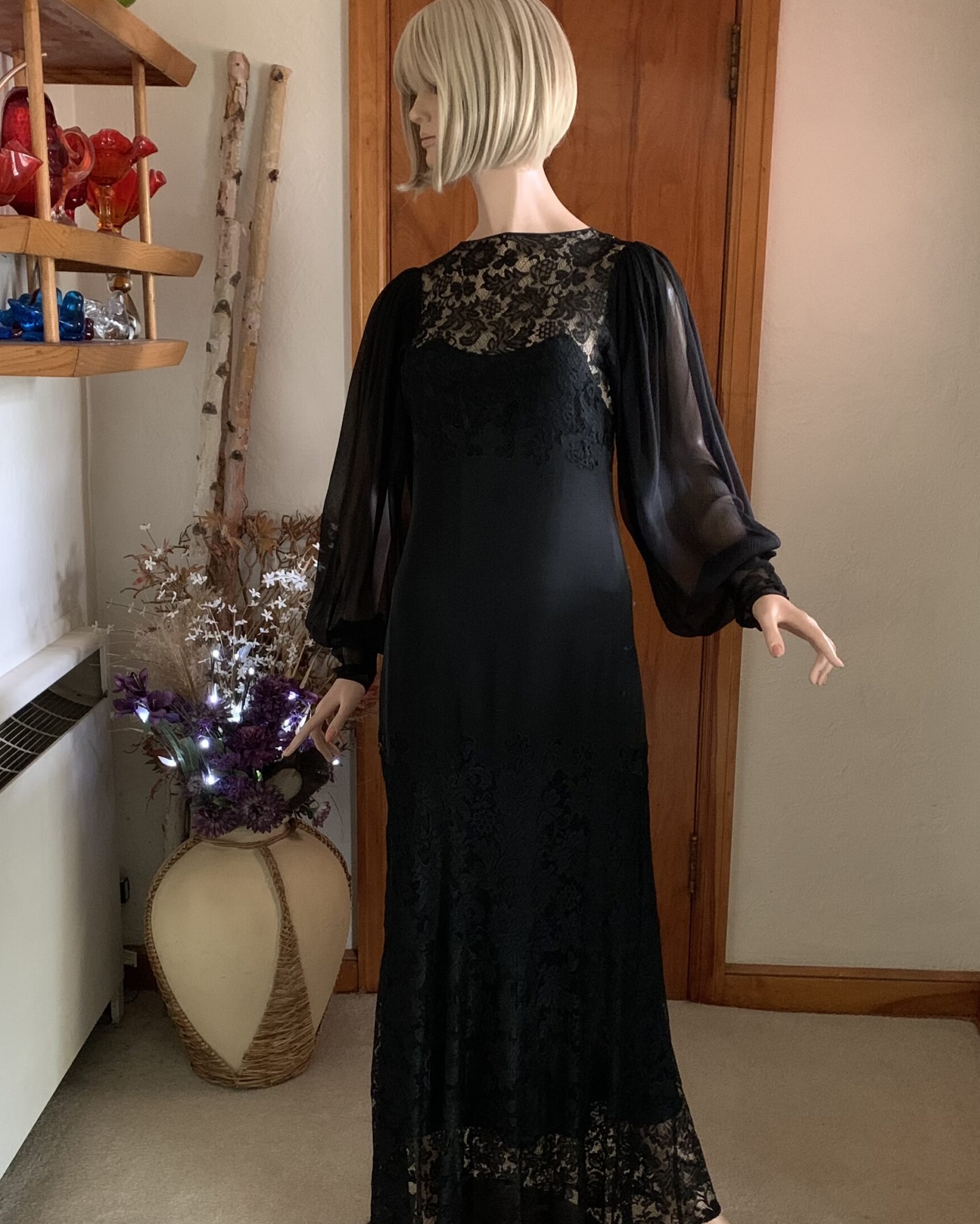 Vintage black evening gown with sheer lace back and dramatic chiffon sleeves displayed on mannequin