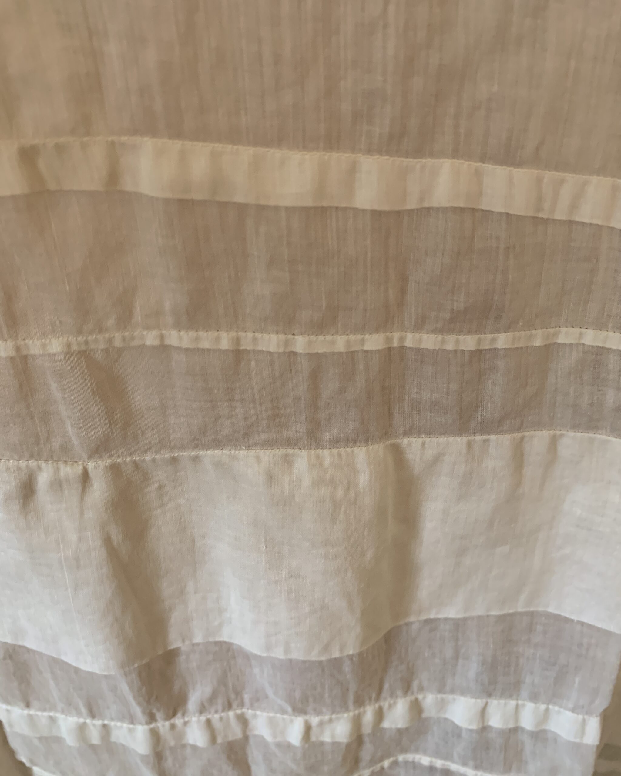 Detail of sheer insertion bands and horizontal trim near the hem of an Edwardian white cotton day dress.