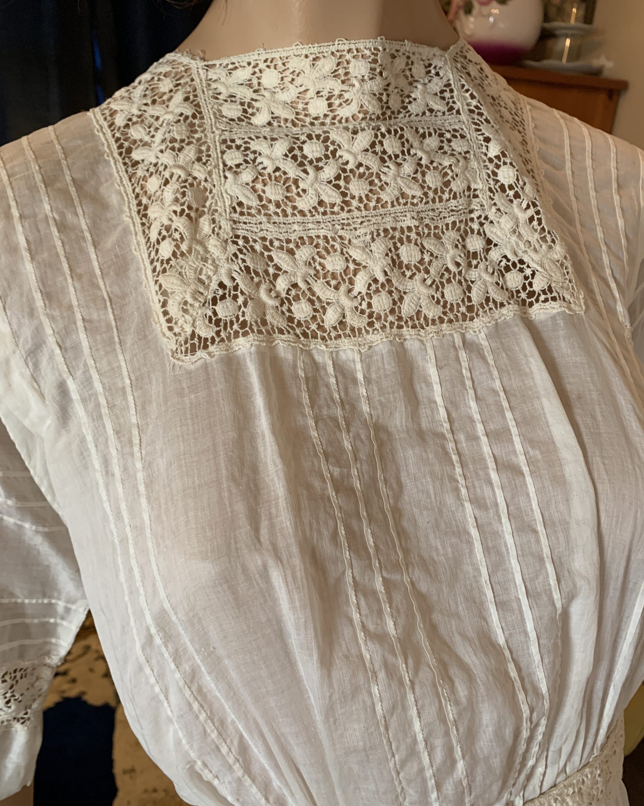 Close-up of handmade lace yoke and pintucked cotton bodice on an Edwardian day dress.