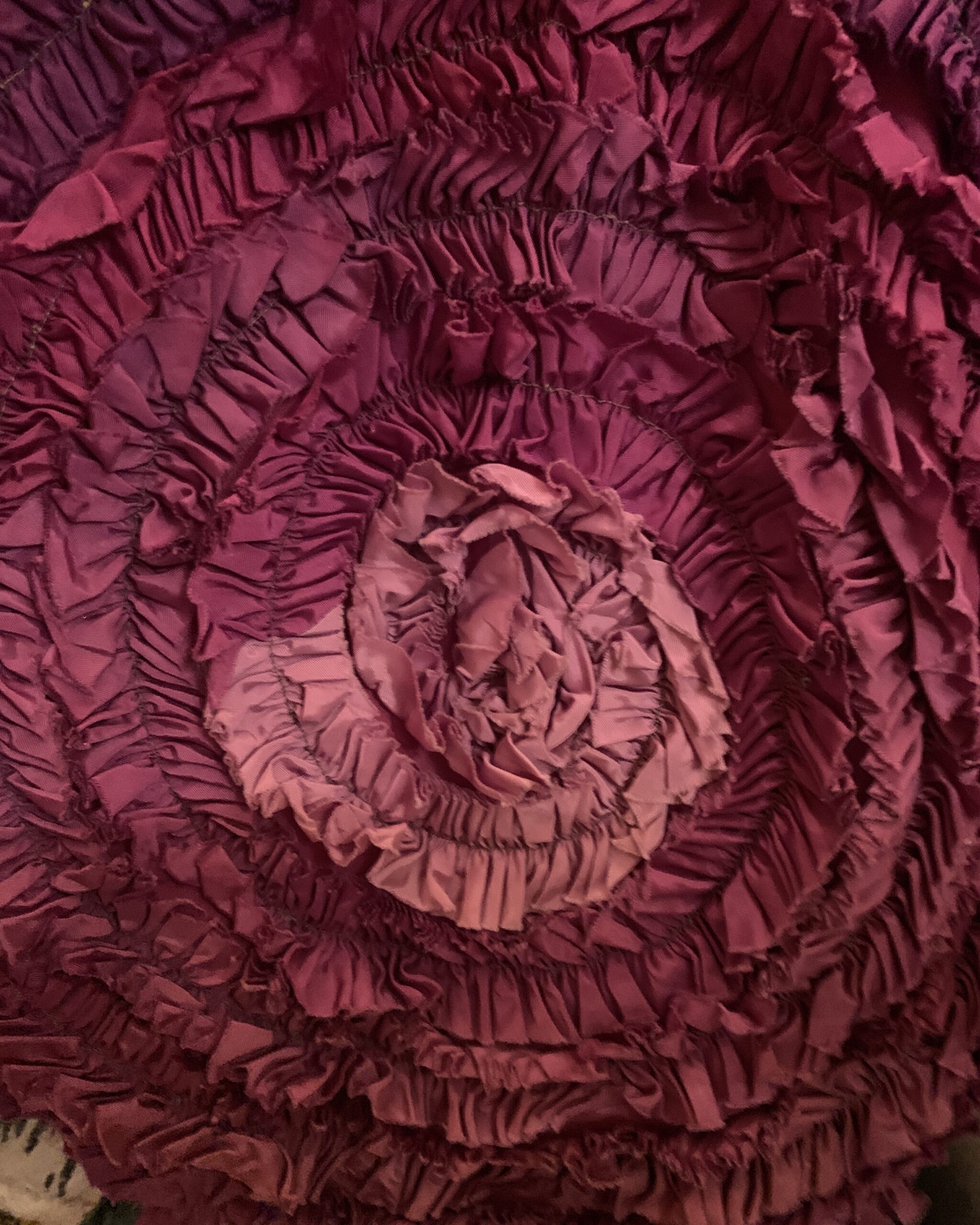 Close-up of dimensional gathered rosette trim and textured fabric detail on magenta vintage evening gown hem.