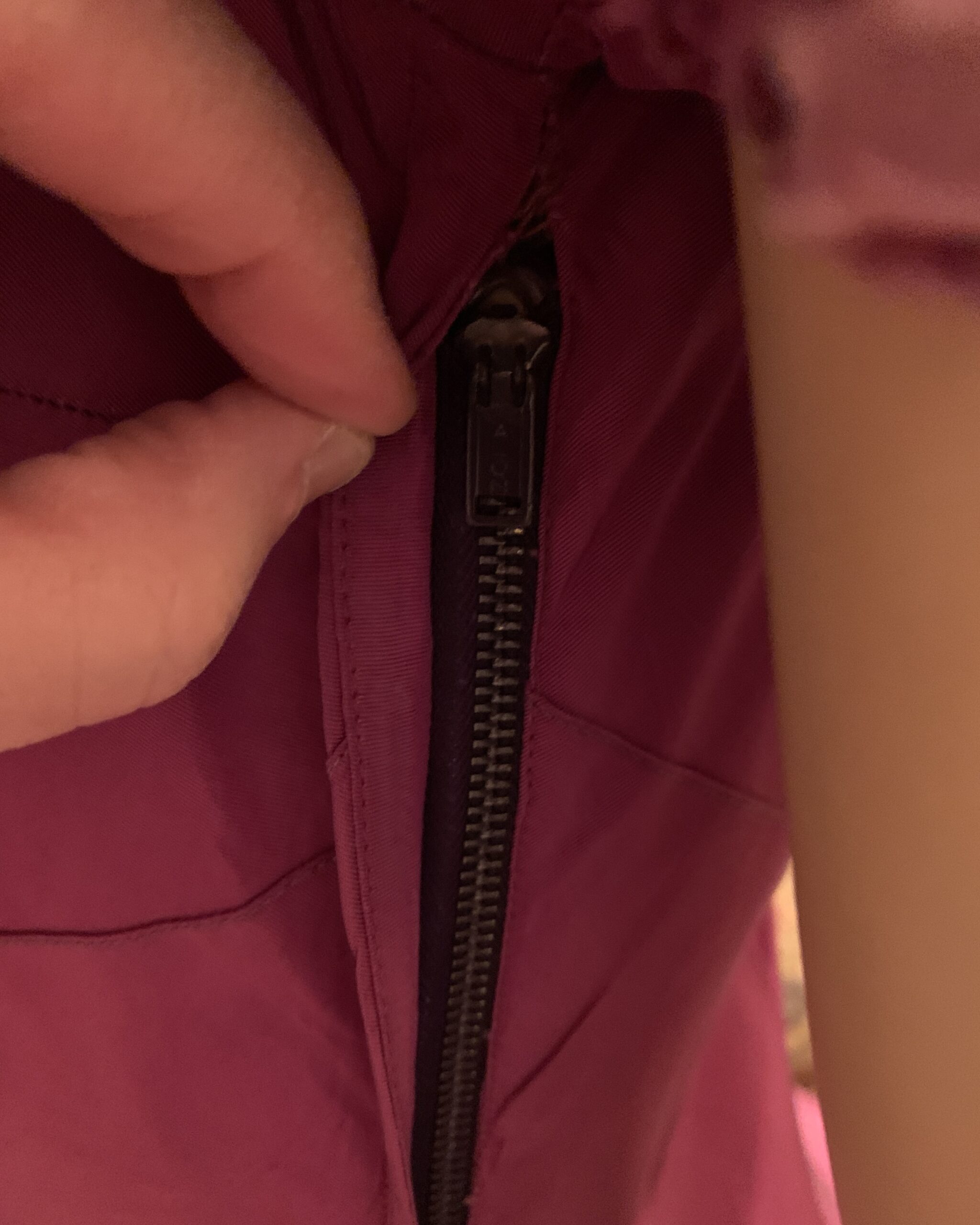 Close-up of vintage metal zipper construction on magenta evening gown.