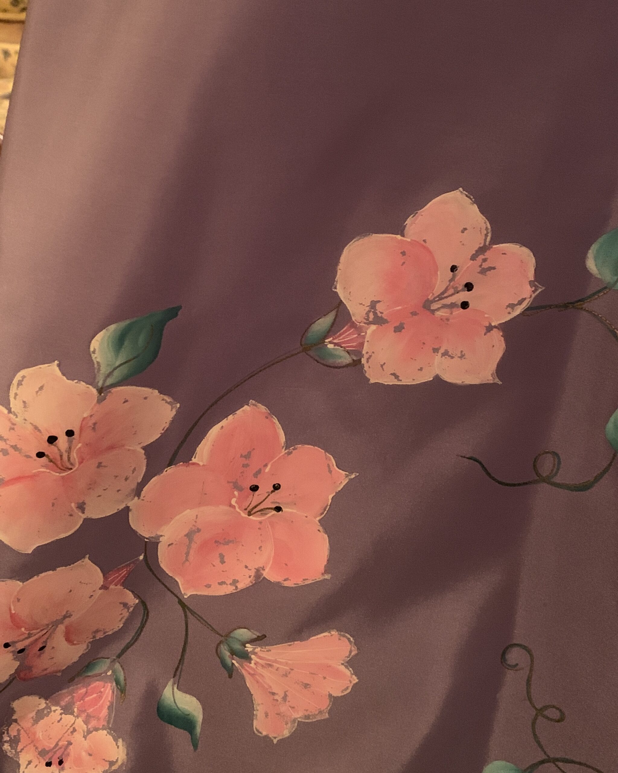 Close-up of the hand-painted pink blossoms and green vines decorating the hem of a vintage lavender Elizabeth Arden dress.