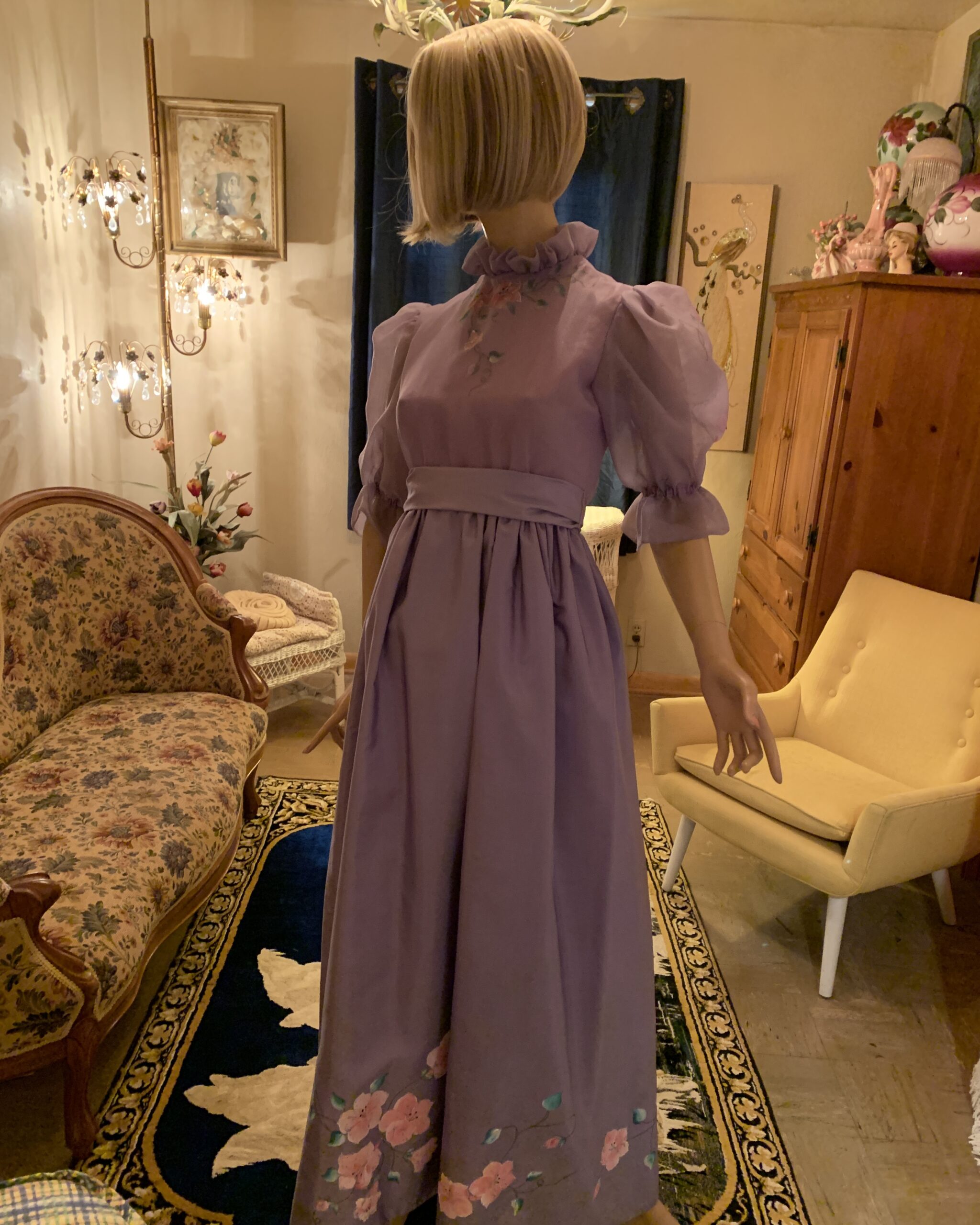 Front view of a vintage Elizabeth Arden lavender prairie-style maxi dress featuring sheer puff sleeves, an empire waist, and hand-painted floral artwork.