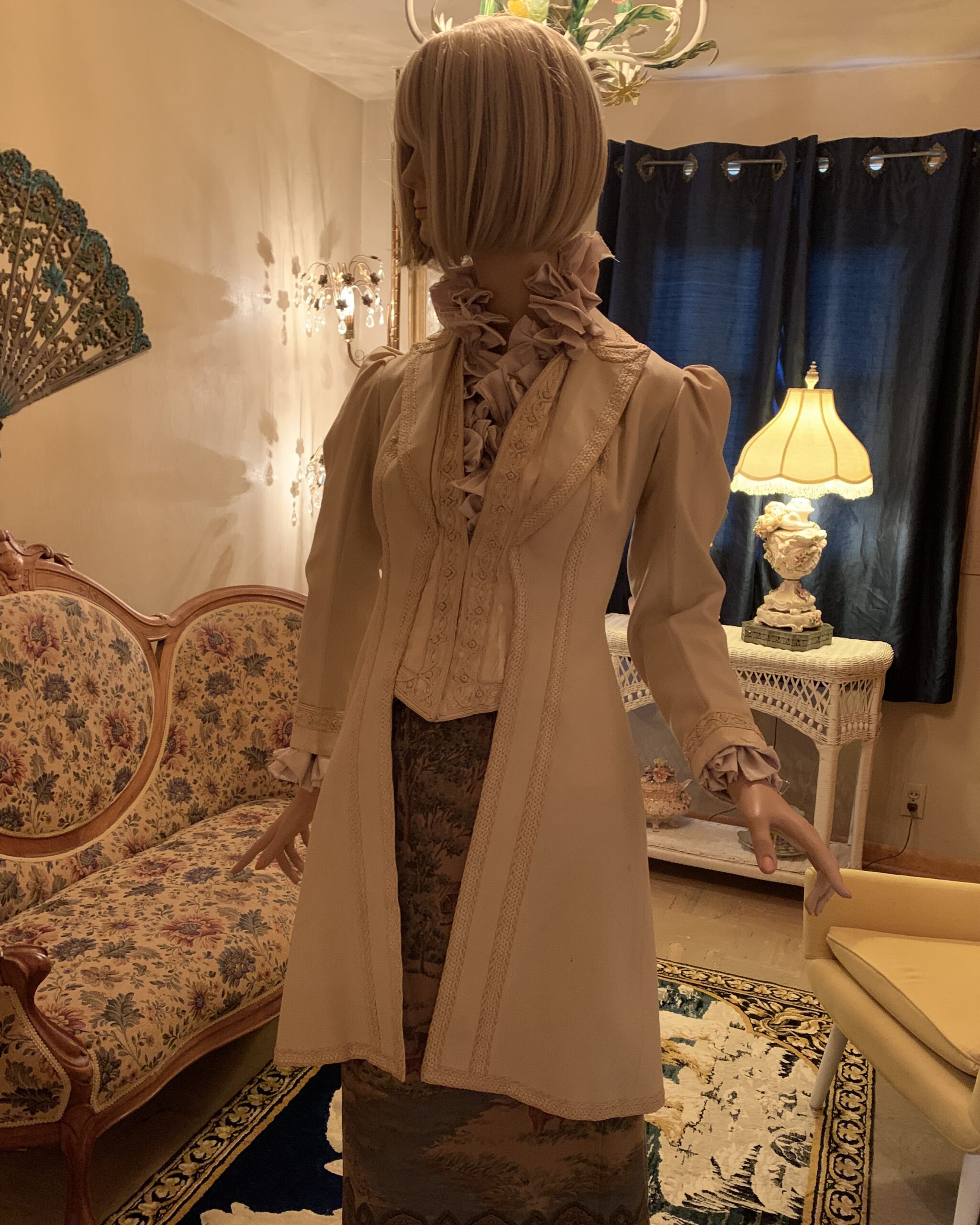 Late Victorian ivory wool walking coat shown from an angled front view highlighting the fitted waist, soutache detailing, and puffed sleeves.