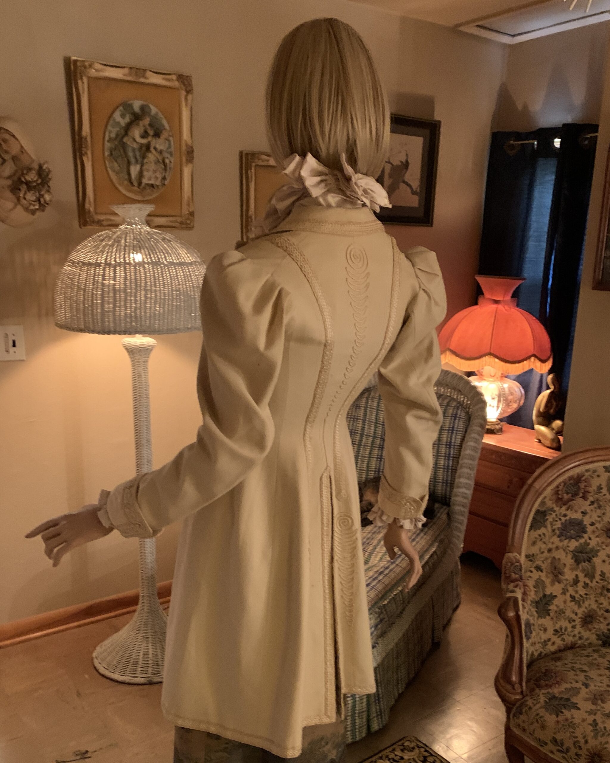 Back view of a late Victorian ivory wool walking coat featuring an elaborate soutache braid design and shaped back seams.