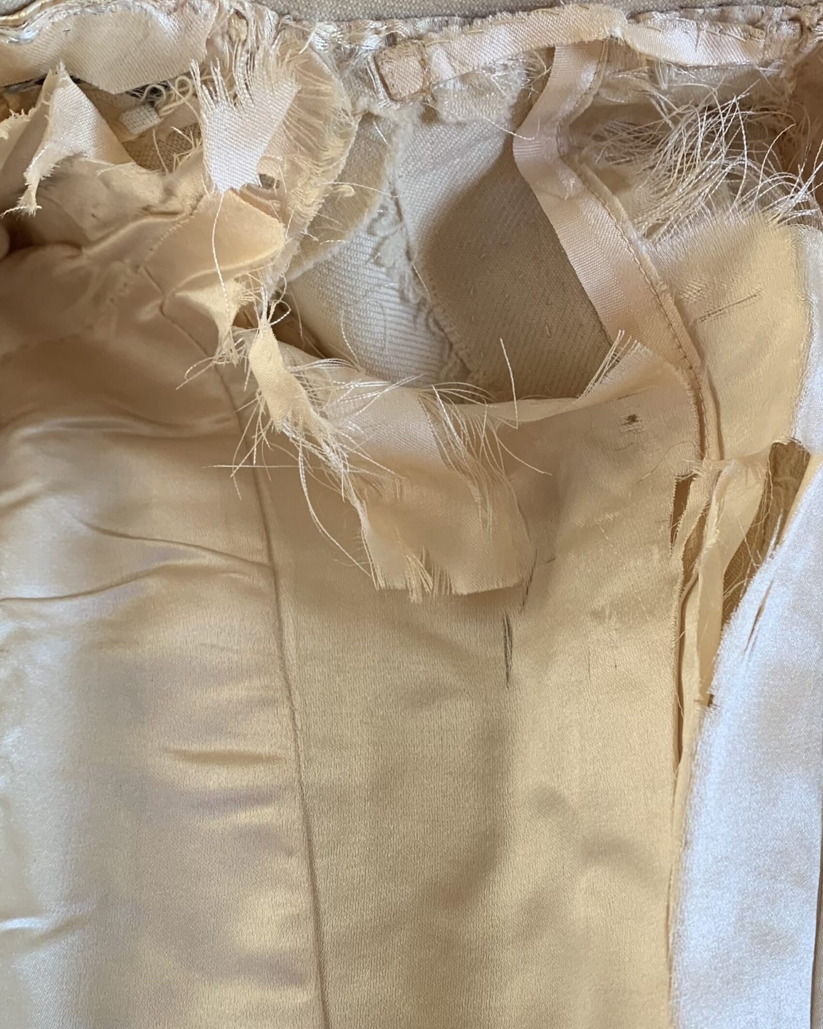 Interior view of a late Victorian ivory wool walking coat showing the original satin lining and hand-finished construction.