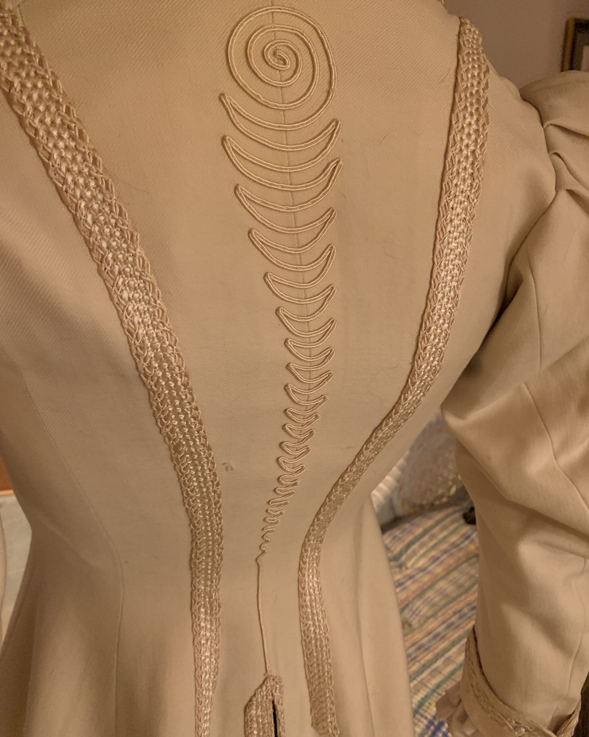 Close-up of the decorative soutache braid running down the back of a late Victorian ivory wool walking coat.