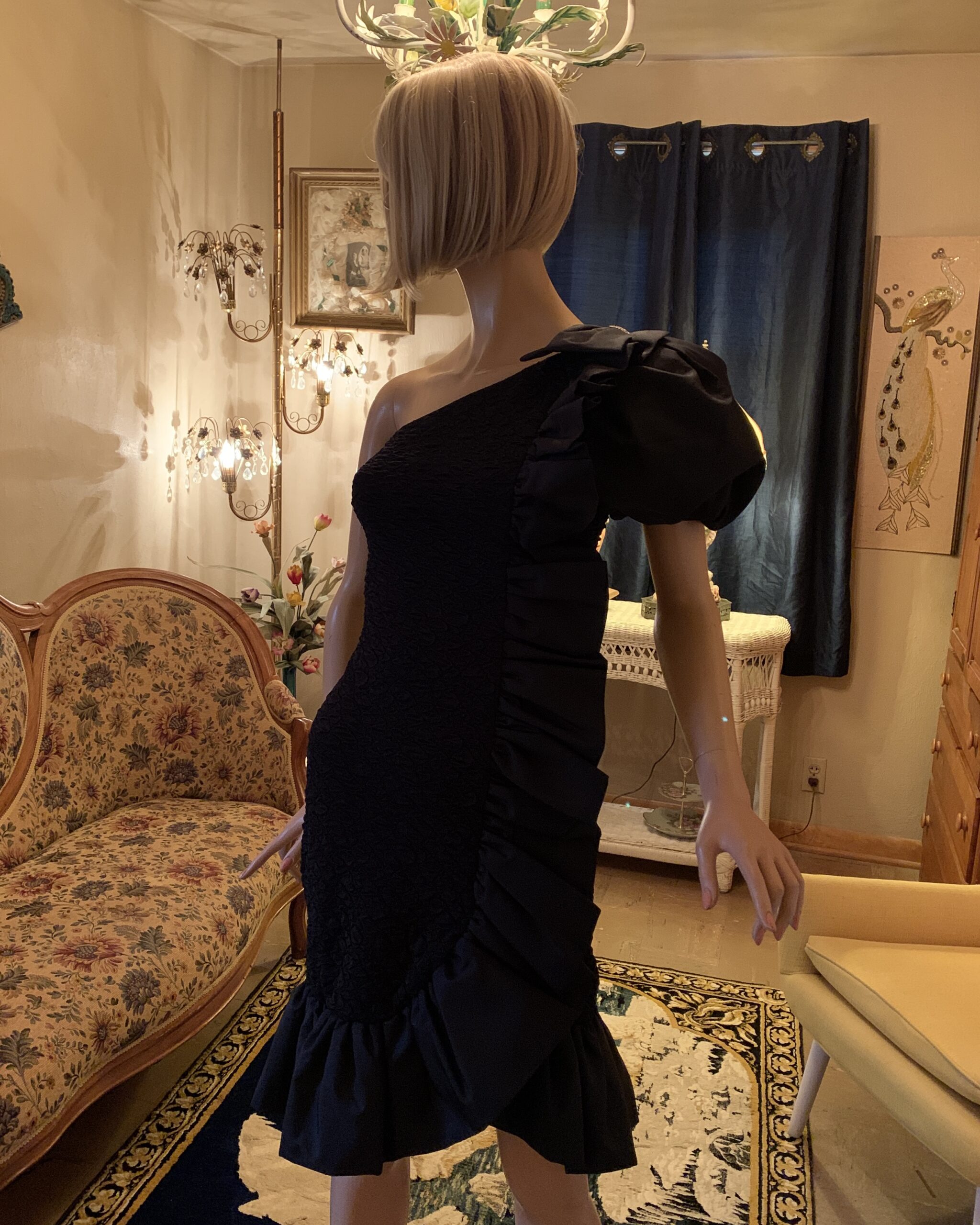 Angled front view of Nancy Bracoloni black one shoulder cocktail dress with sculptural puff sleeve and asymmetrical silhouette.