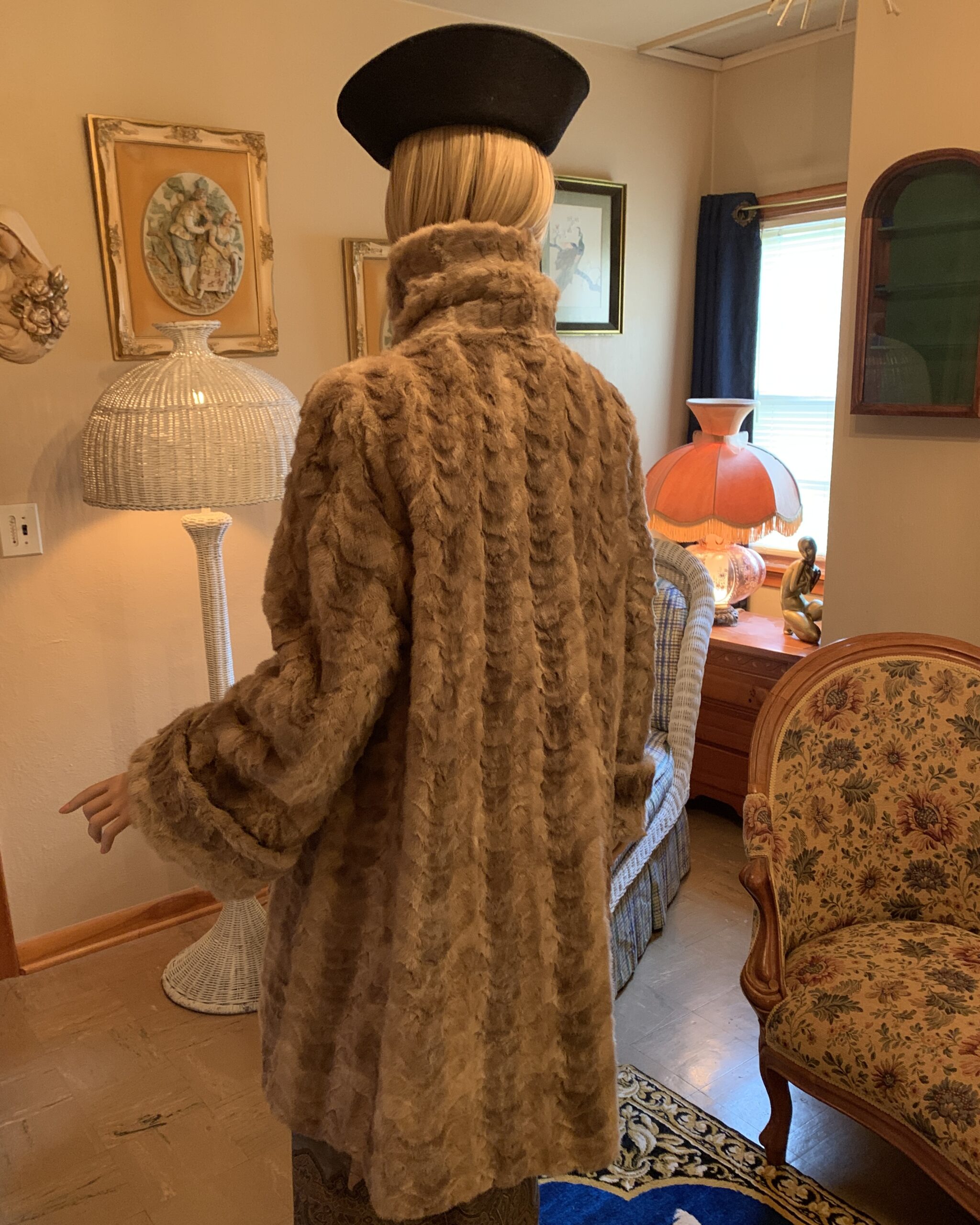 Back view of a vintage faux fur coat featuring a full silhouette, high collar, and textured fur pattern.