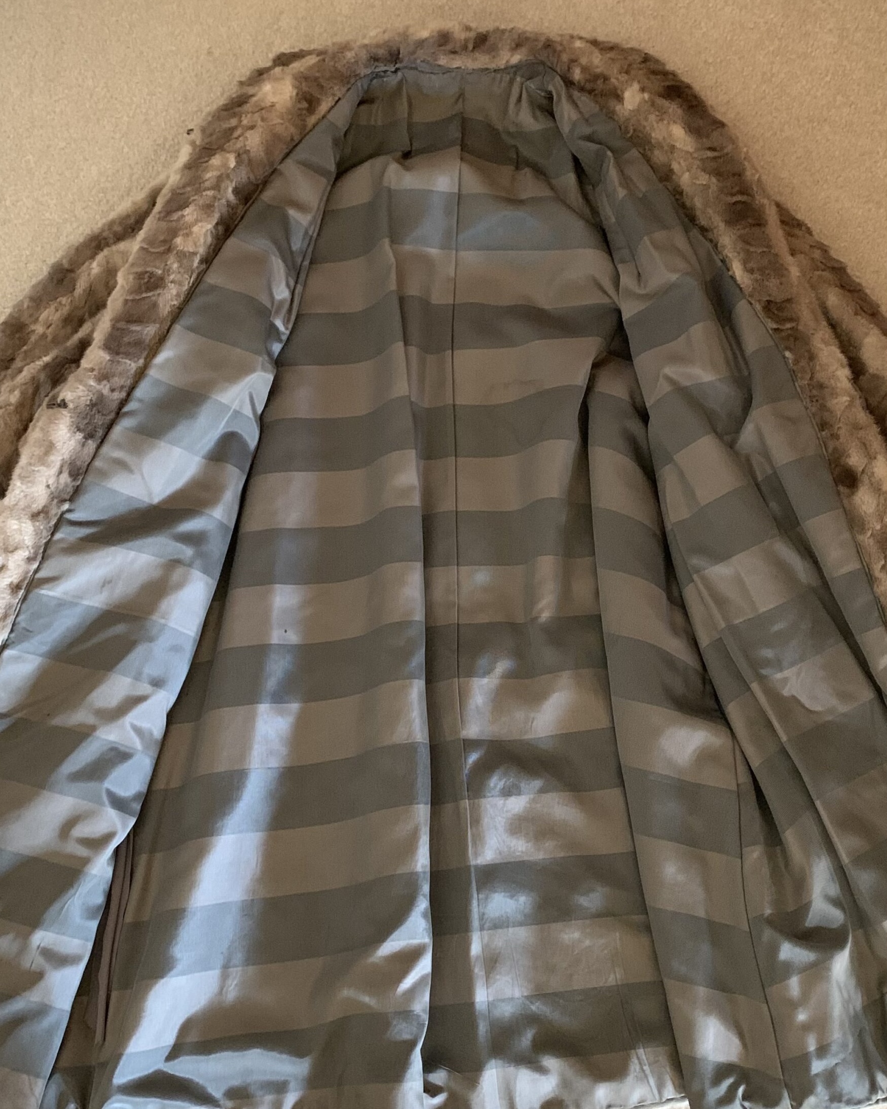 Interior view of a vintage faux fur coat showing the striped satin lining and finished construction.