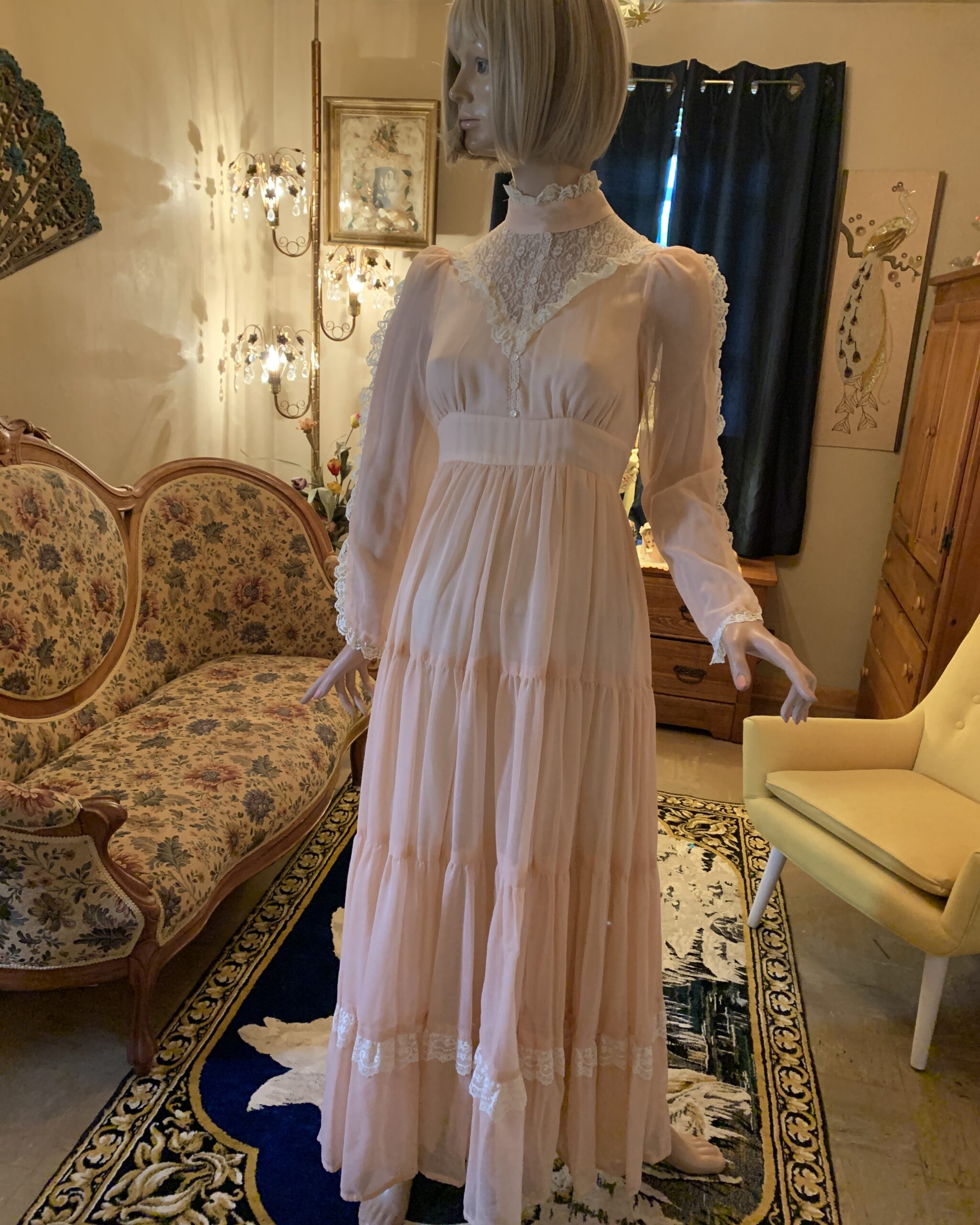 Vintage Gunne Sax peach prairie dress with lace bib neckline, sheer sleeves, and a flowing tiered skirt shown from the front.