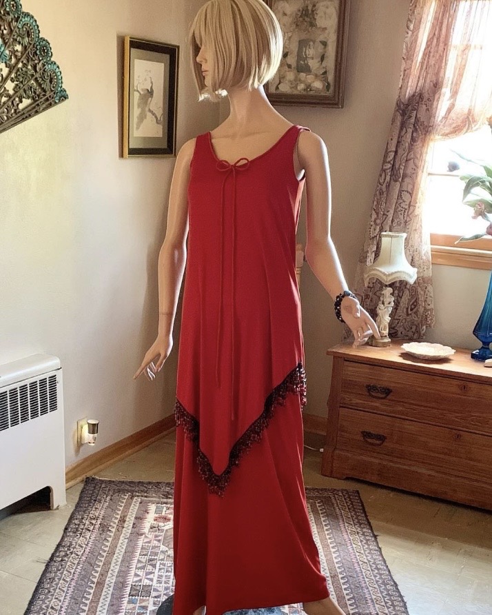 Vintage Jack Bryan by Dupuis red evening gown with asymmetrical beaded overlay and dangling fringe detail displayed on mannequin in interior setting.