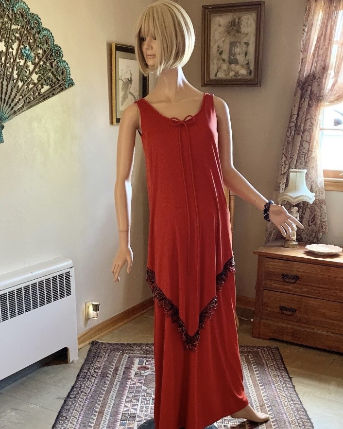 Side angle of vintage late 1960s red evening gown with asymmetrical beaded fringe overlay and fluid column silhouette.
