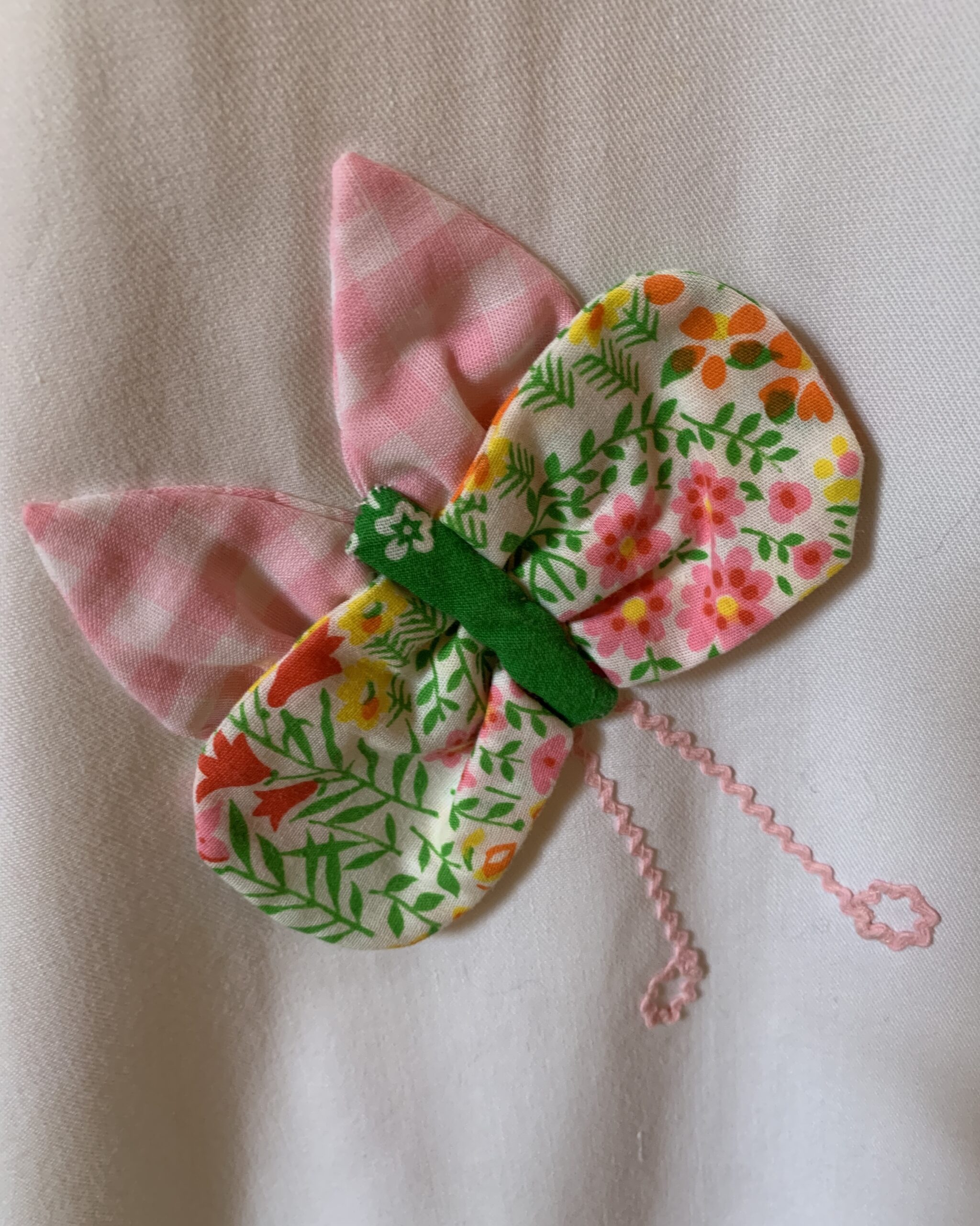 Close-up of the handcrafted butterfly appliqué on the vintage Catherine Carr skirt made from floral and pink gingham fabrics with pink antennae.