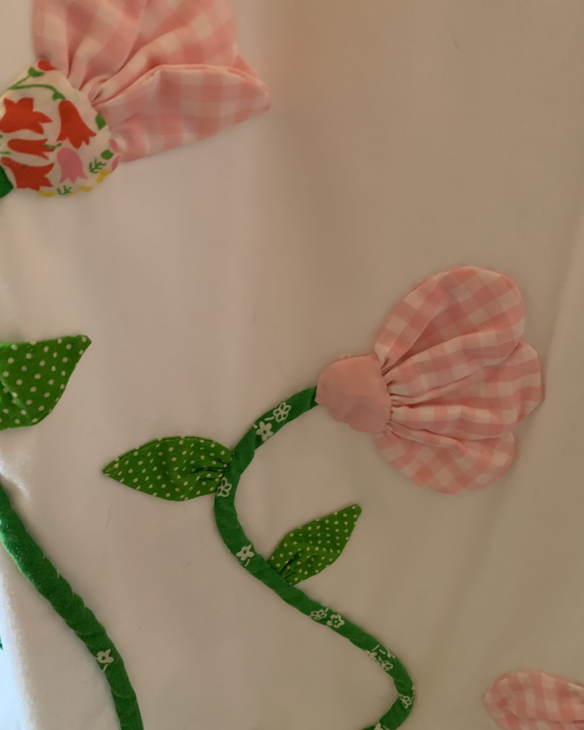 Close-up of the dimensional pink gingham flower appliqués with green fabric vines and leaves on the vintage Catherine Carr skirt.