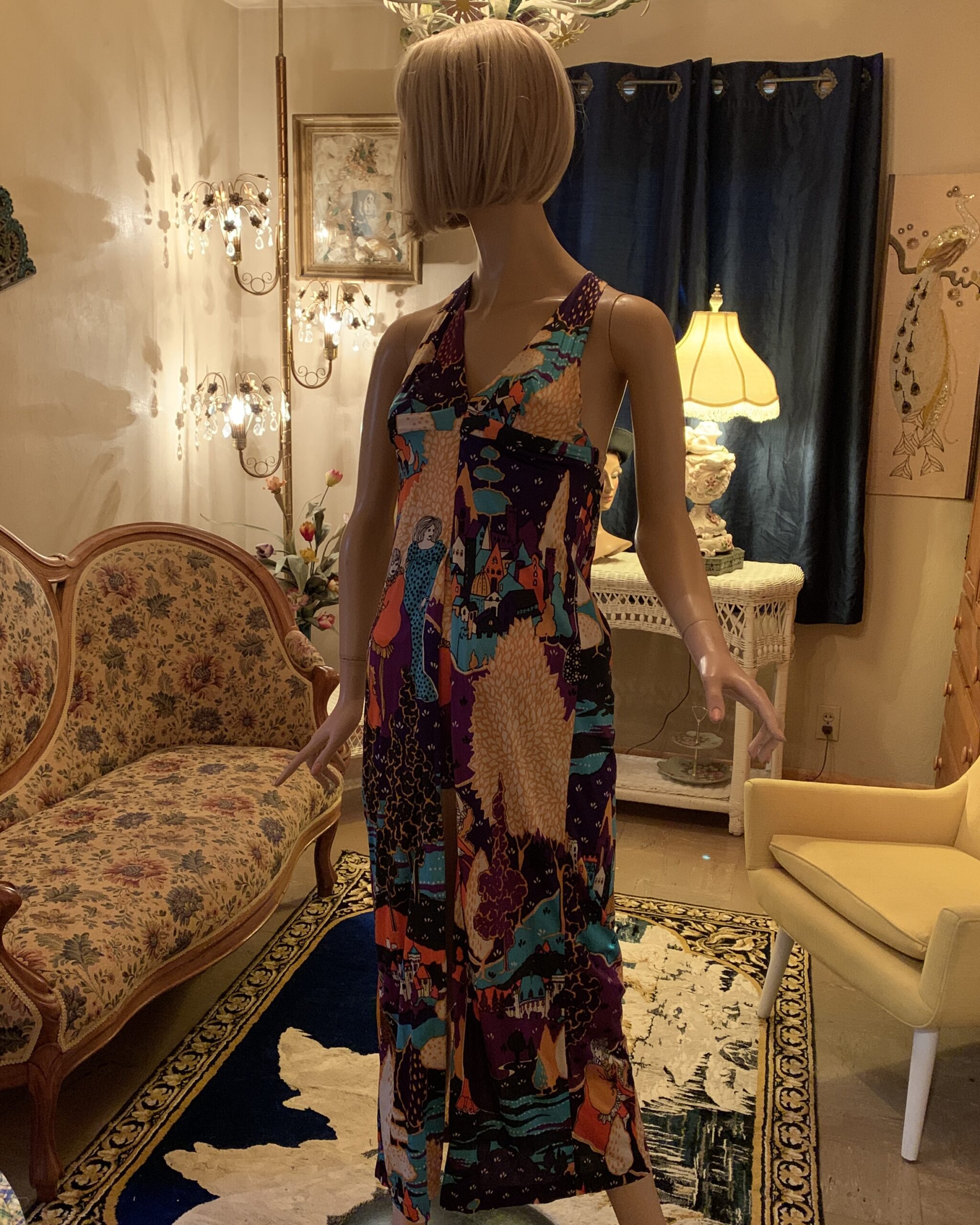 Angled front view of a vintage novelty print halter two-piece set with vibrant purple, turquoise, orange, and cream scenic print.