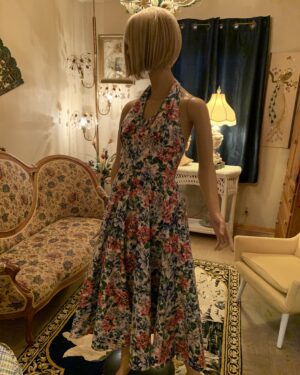 1980s Karen Alexander floral halter midi dress with an open back, draped cowl neckline, and full gathered skirt in a pink, lavender, blue, and green floral print.