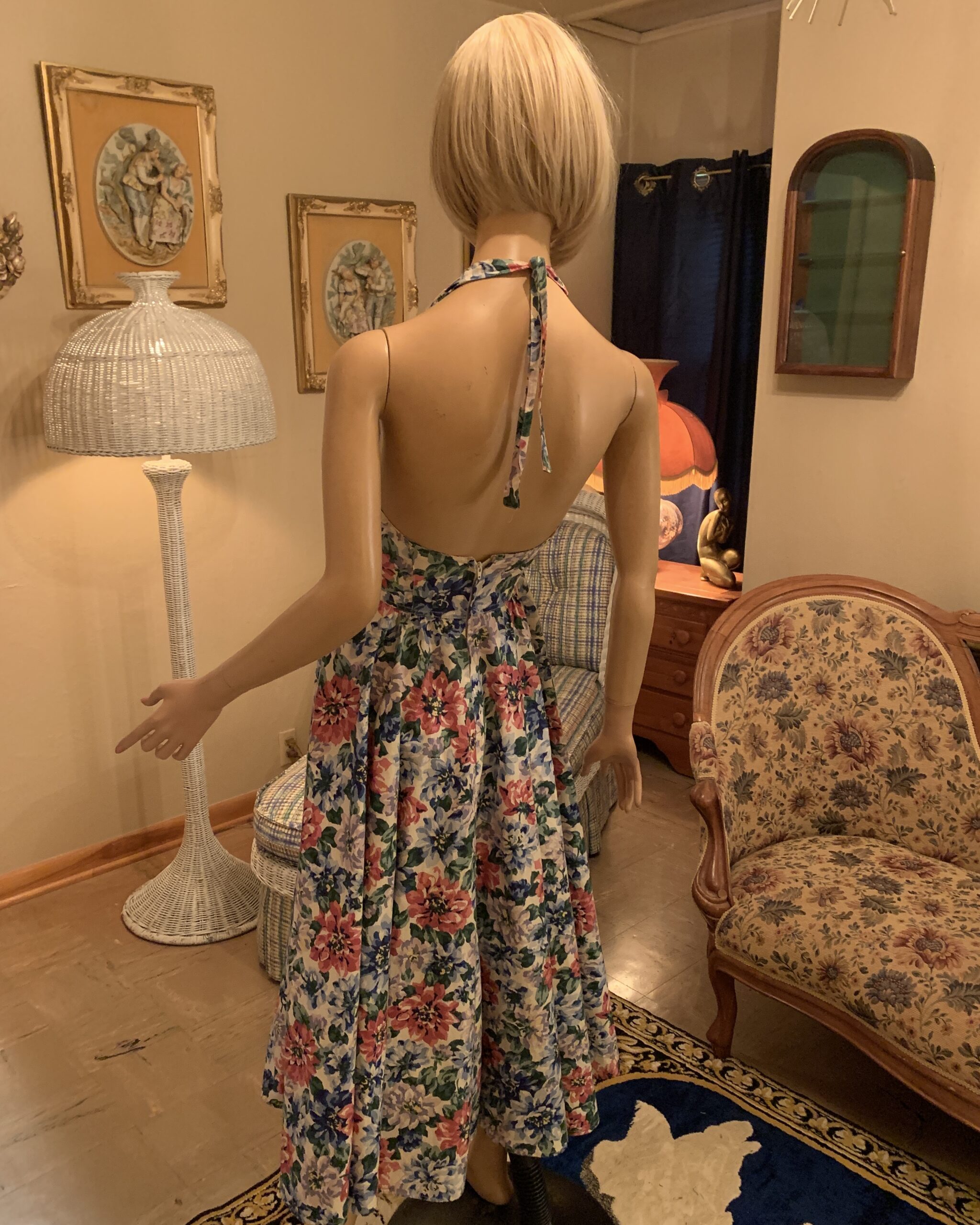 1980s Karen Alexander floral halter midi dress with an open back, draped cowl neckline, and full gathered skirt in a pink, lavender, blue, and green floral print.