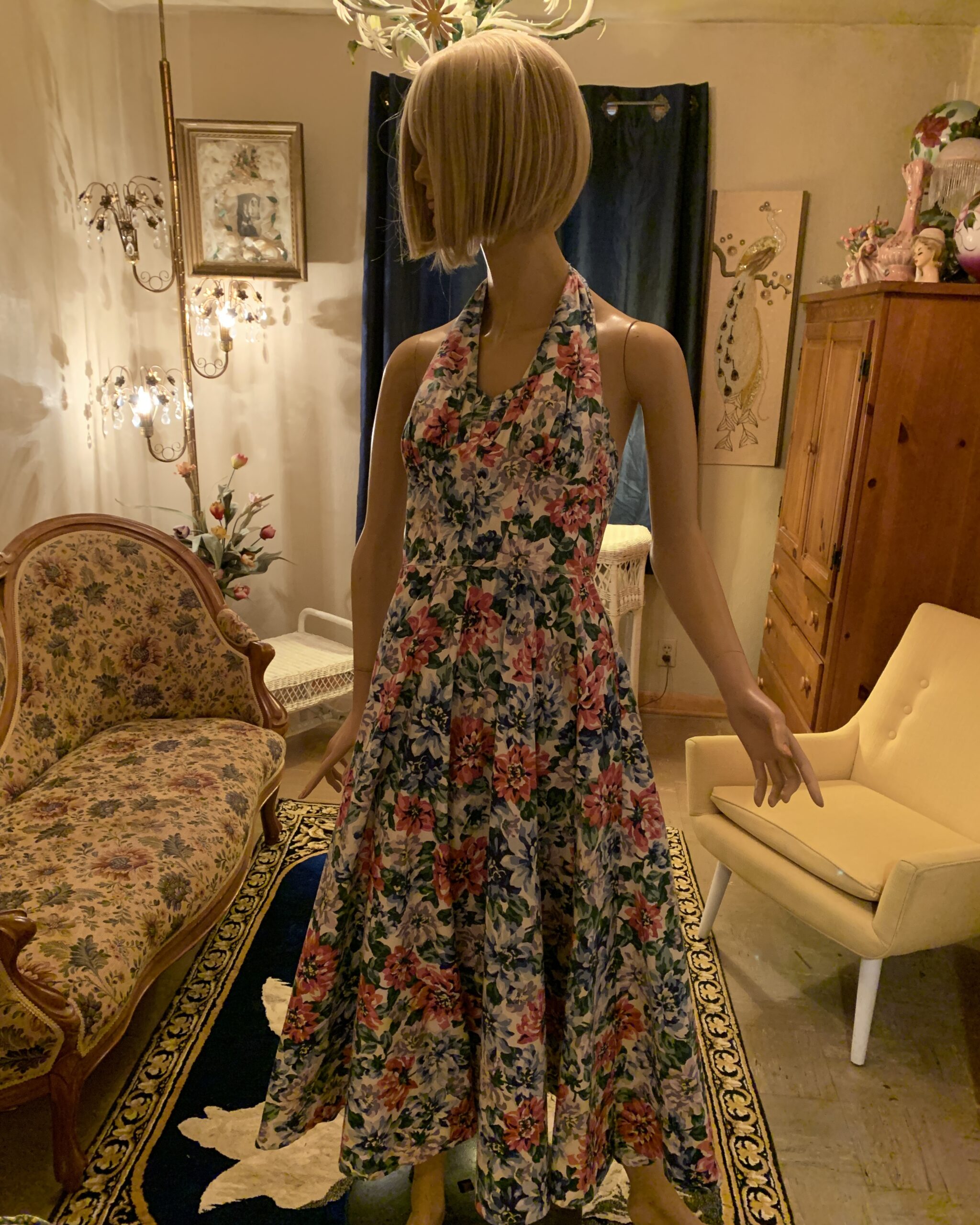 1980s Karen Alexander floral halter midi dress with an open back, draped cowl neckline, and full gathered skirt in a pink, lavender, blue, and green floral print.