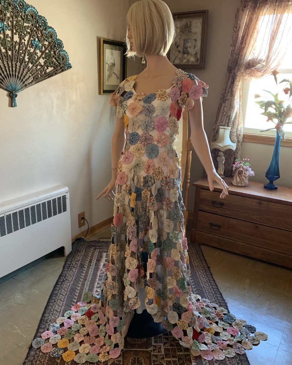Antique yo-yo quilt gown with trailing hem displayed on mannequin in historic interior