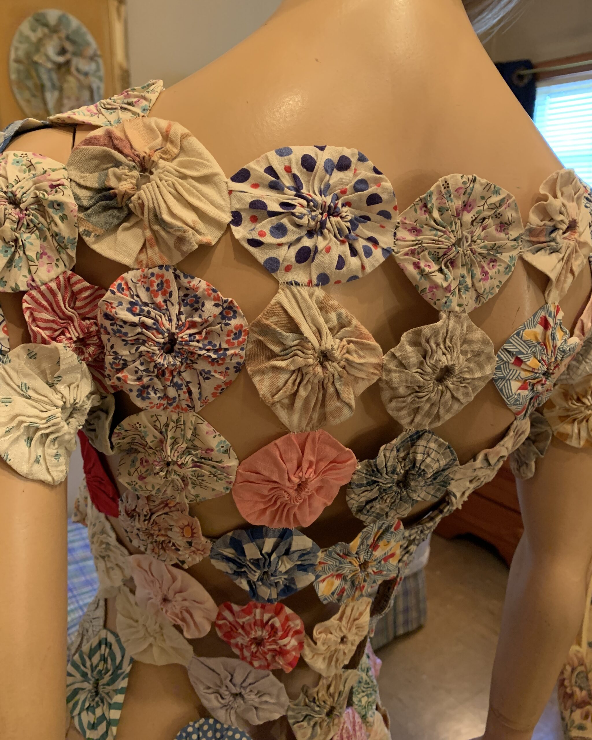Close-up of the back bodice revealing the open lattice structure formed by interconnected fabric yo-yos.