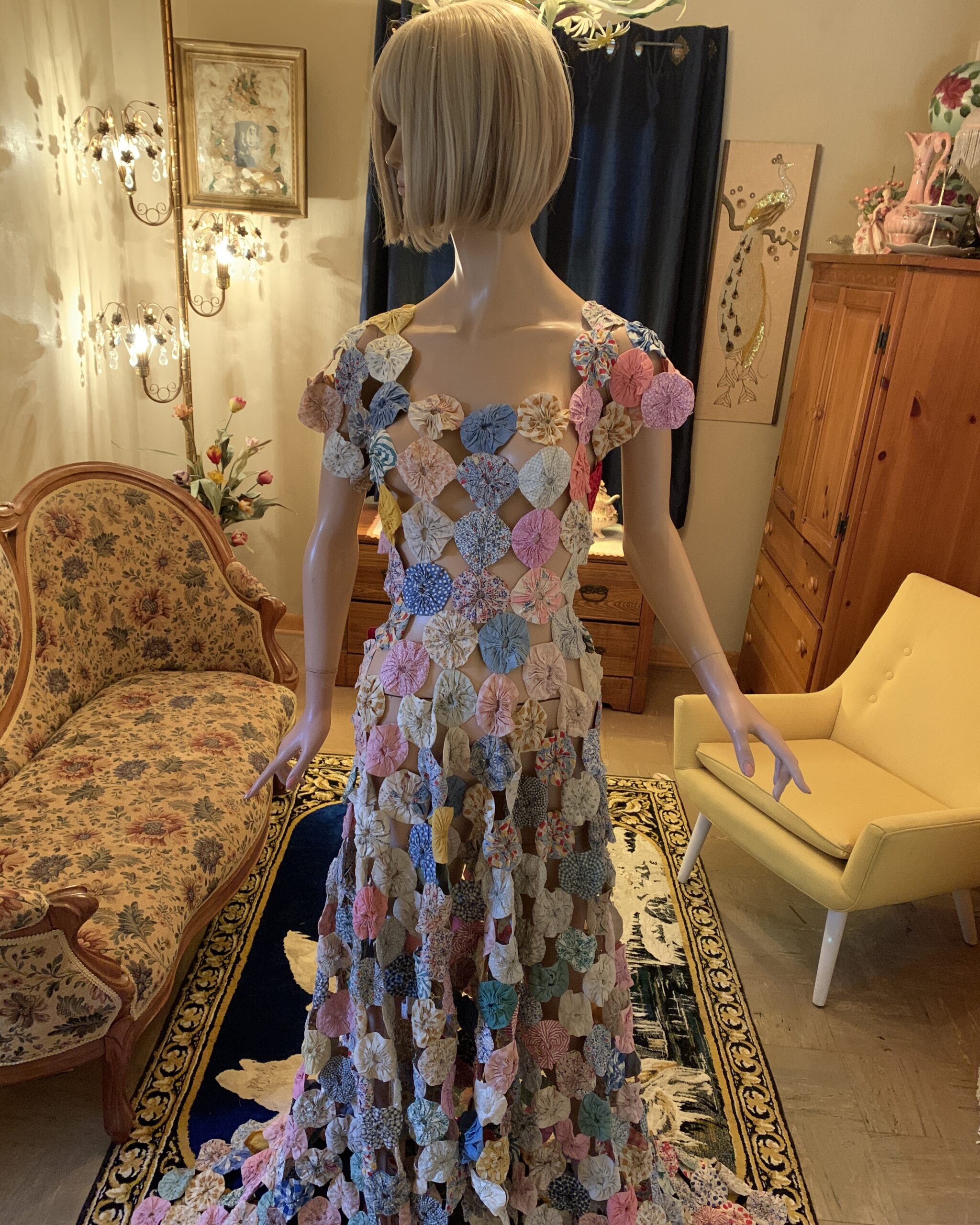 Front view of a handmade yo-yo quilt dress composed of colorful fabric yo-yos joined together to create an openwork gown silhouette.