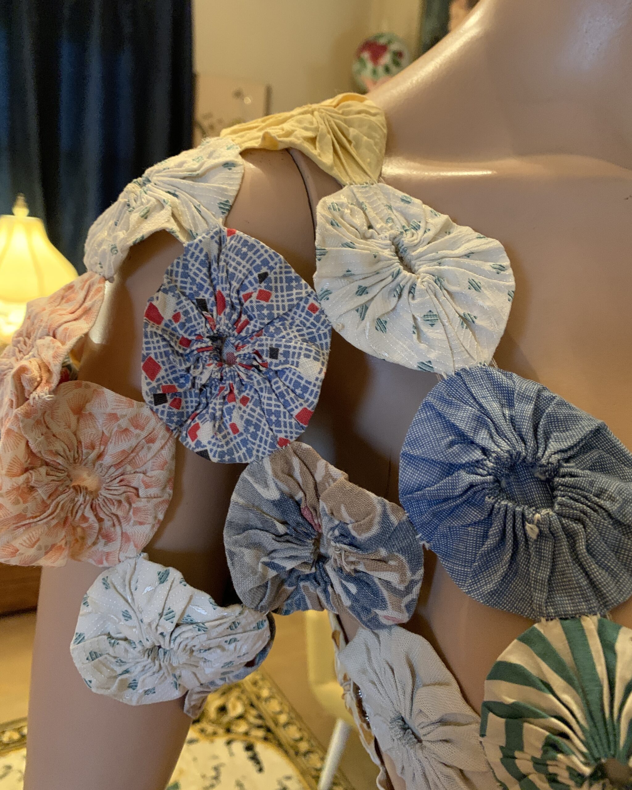 Close-up detail of the shoulder area showing individually gathered fabric yo-yos in assorted vintage prints and colors