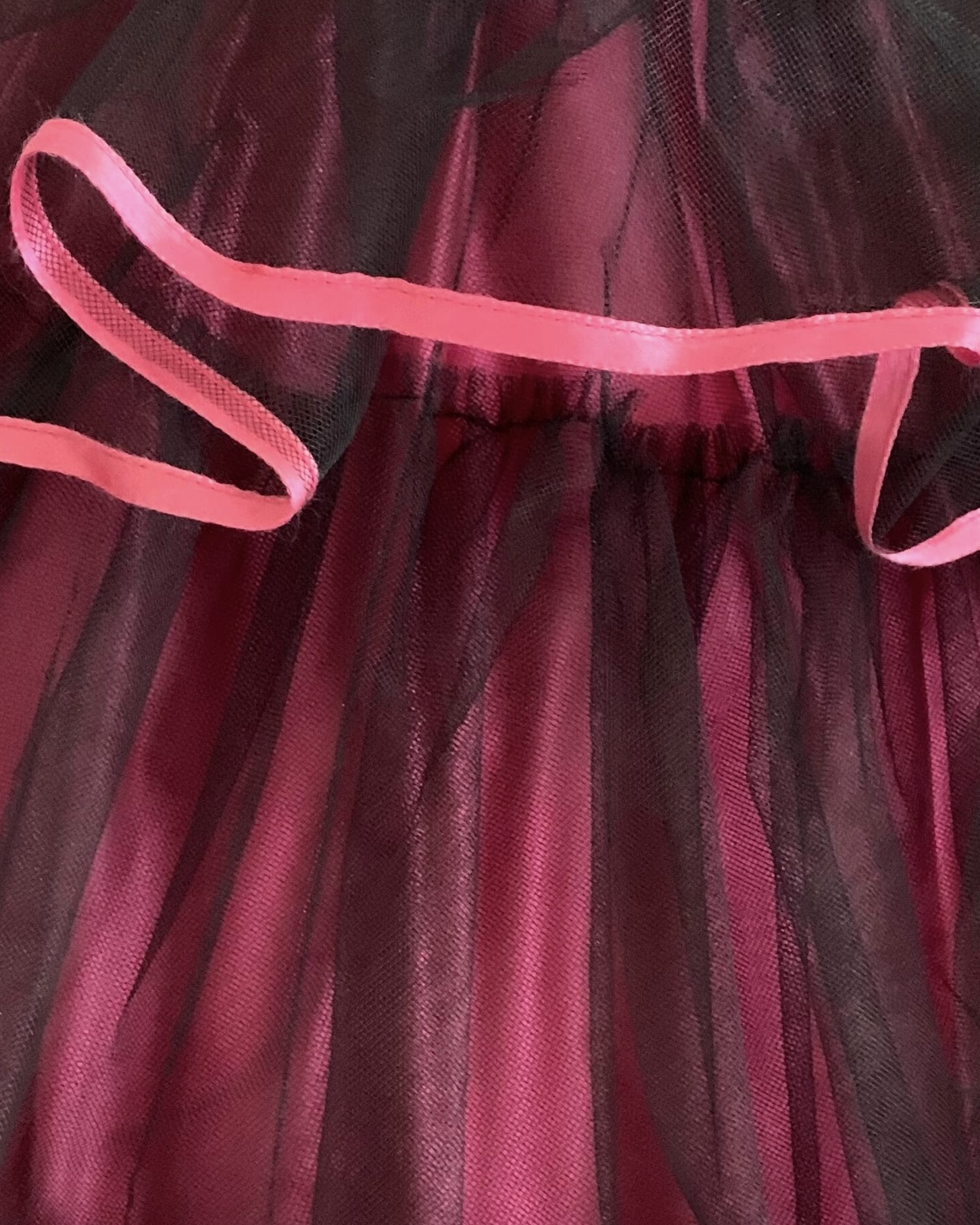 Close-up of gathered black tulle skirt tiers with pink ribbon edging.