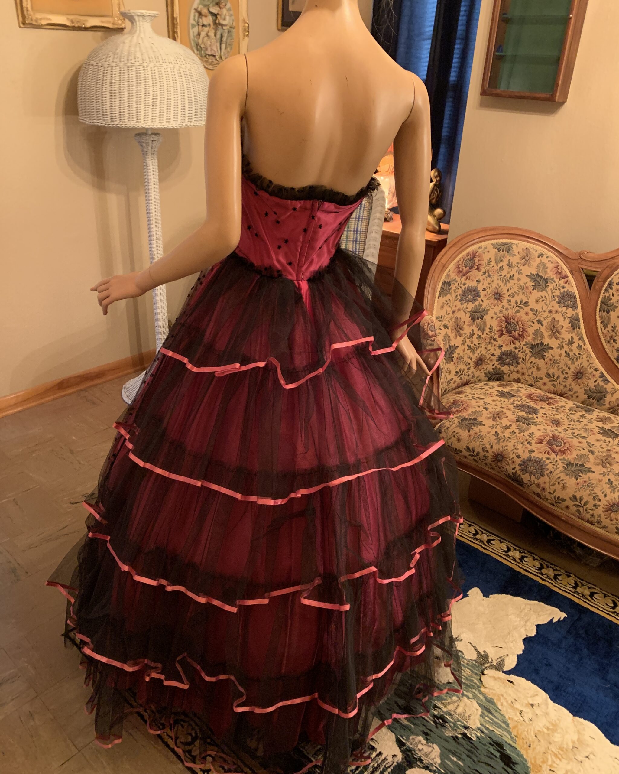 Back view of pink Alfred Angelo gown with black tulle tiers edged in pink ribbon and a center back zipper.