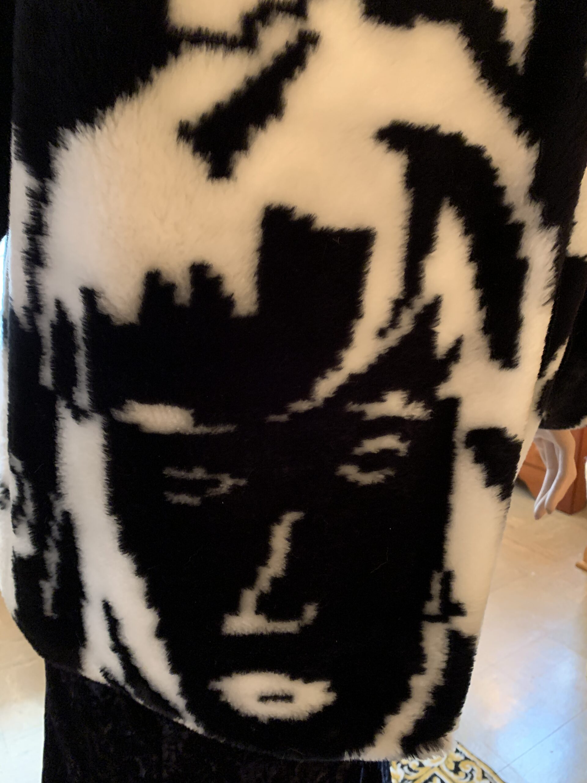 Close-up detail of the abstract face pattern woven into black and white faux fur, inspired by modernist portrait artwork.