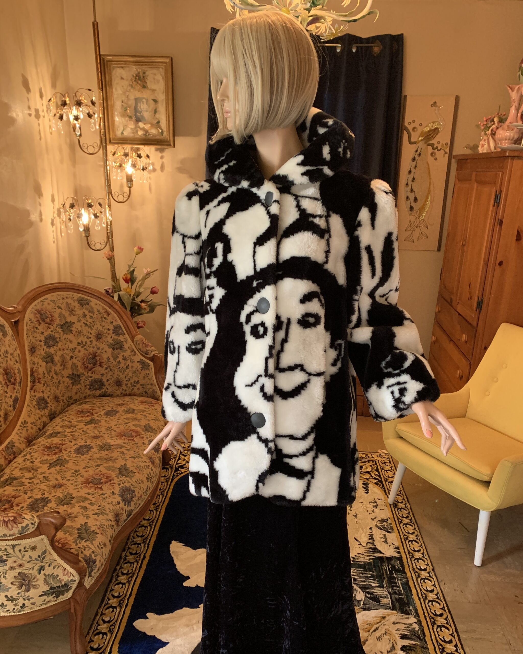 Vintage black and white faux fur coat by Candace Originals featuring oversized abstract face motifs, photographed in a salon interior with floral settee and black velvet gown.