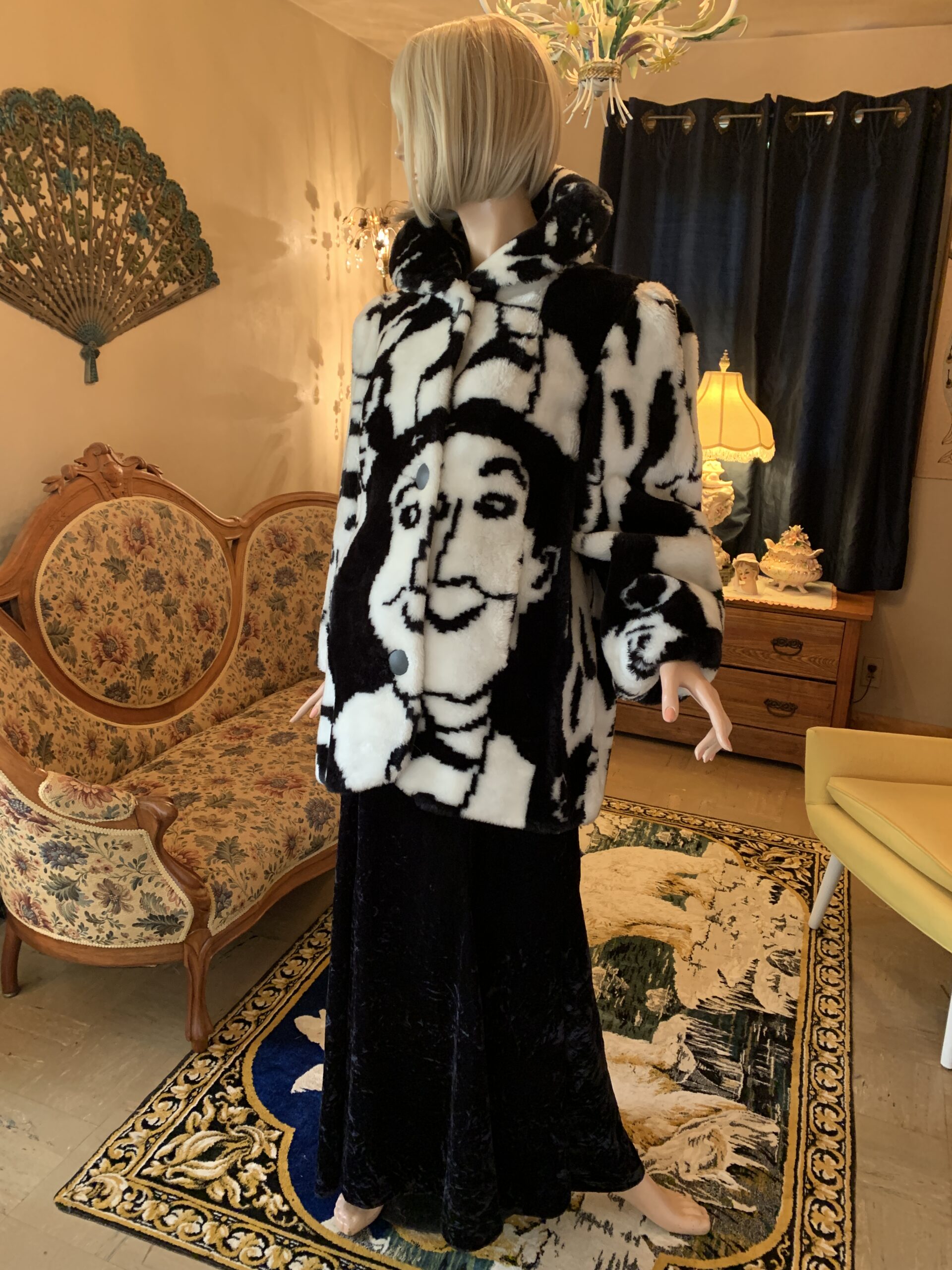 Candace Originals novelty faux fur coat with oversized graphic faces, styled in a salon setting with vintage furnishings and soft lighting.