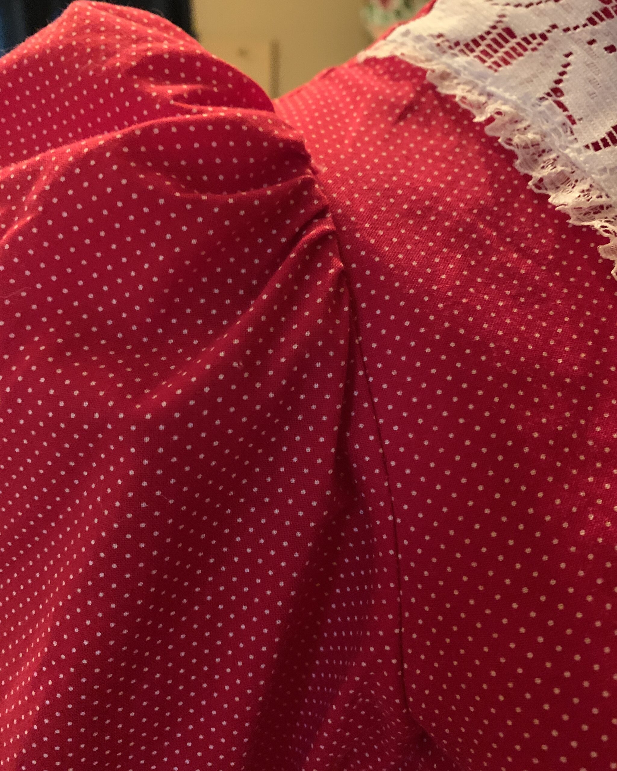 Close-up of red polka dot fabric and gathered puff sleeve construction on handmade vintage prairie dress.