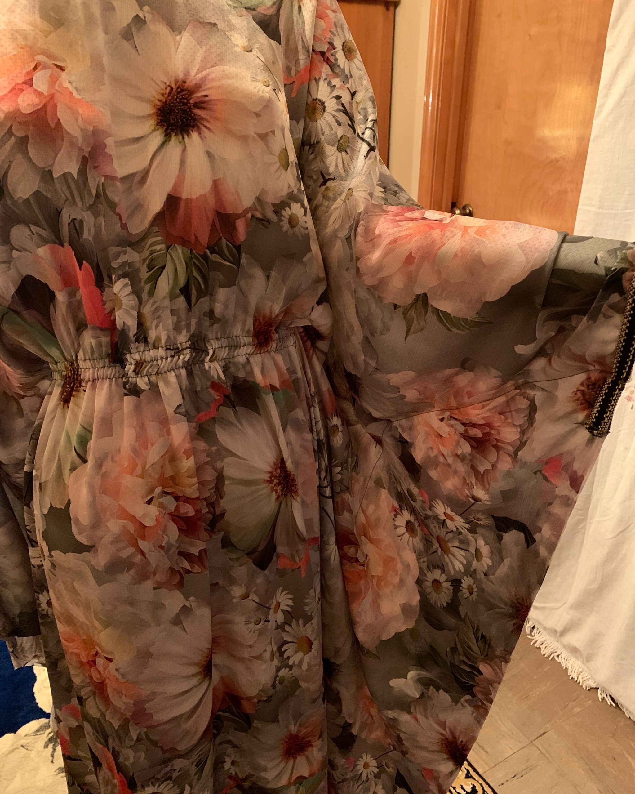 Detail of the dramatic butterfly sleeve on a vintage floral maxi dress with soft pink, white, and gray floral motifs.