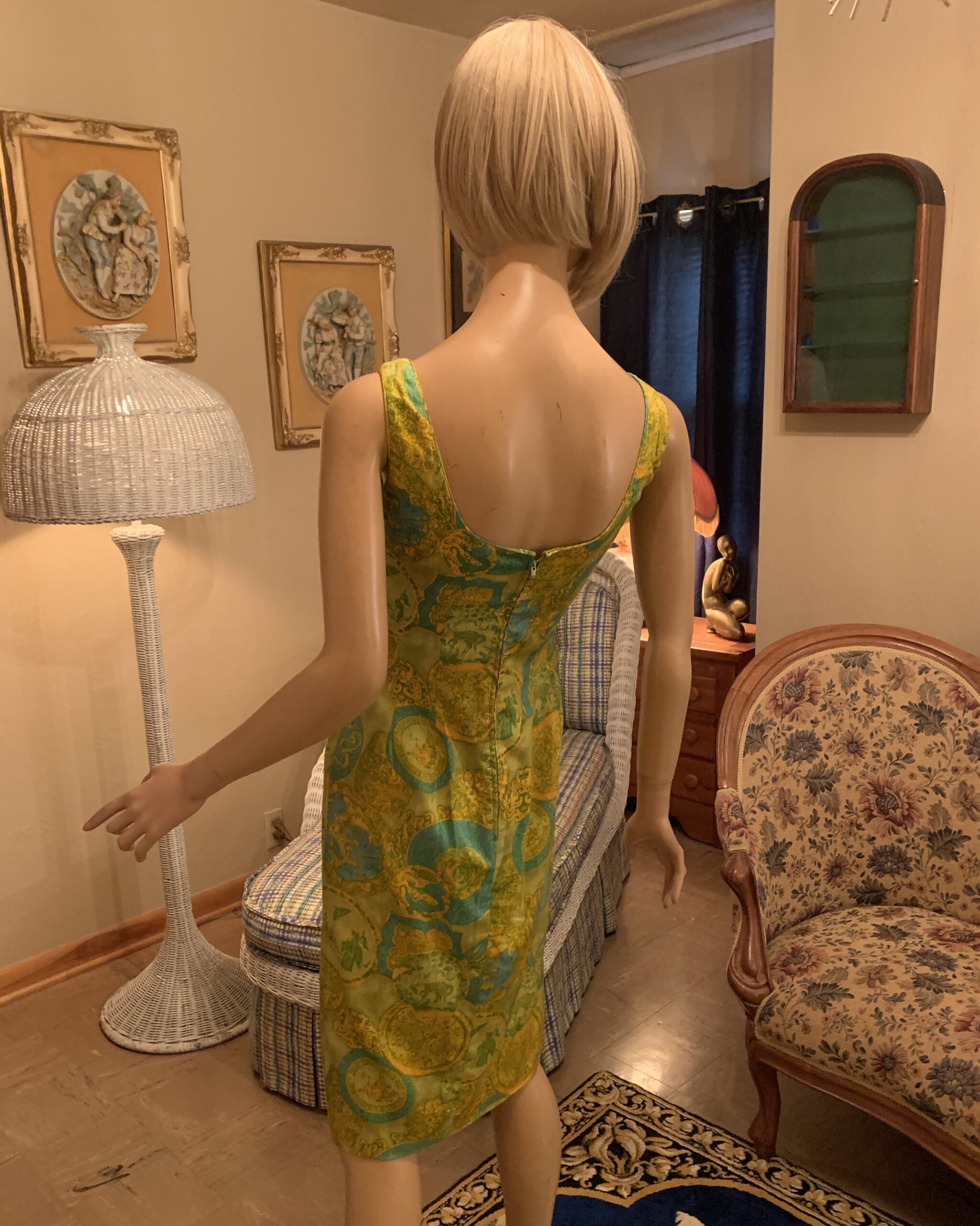 Back view of a late 1970s Dynasty sleeveless novelty print dress with deep scoop back, center zipper, and straight silhouette.