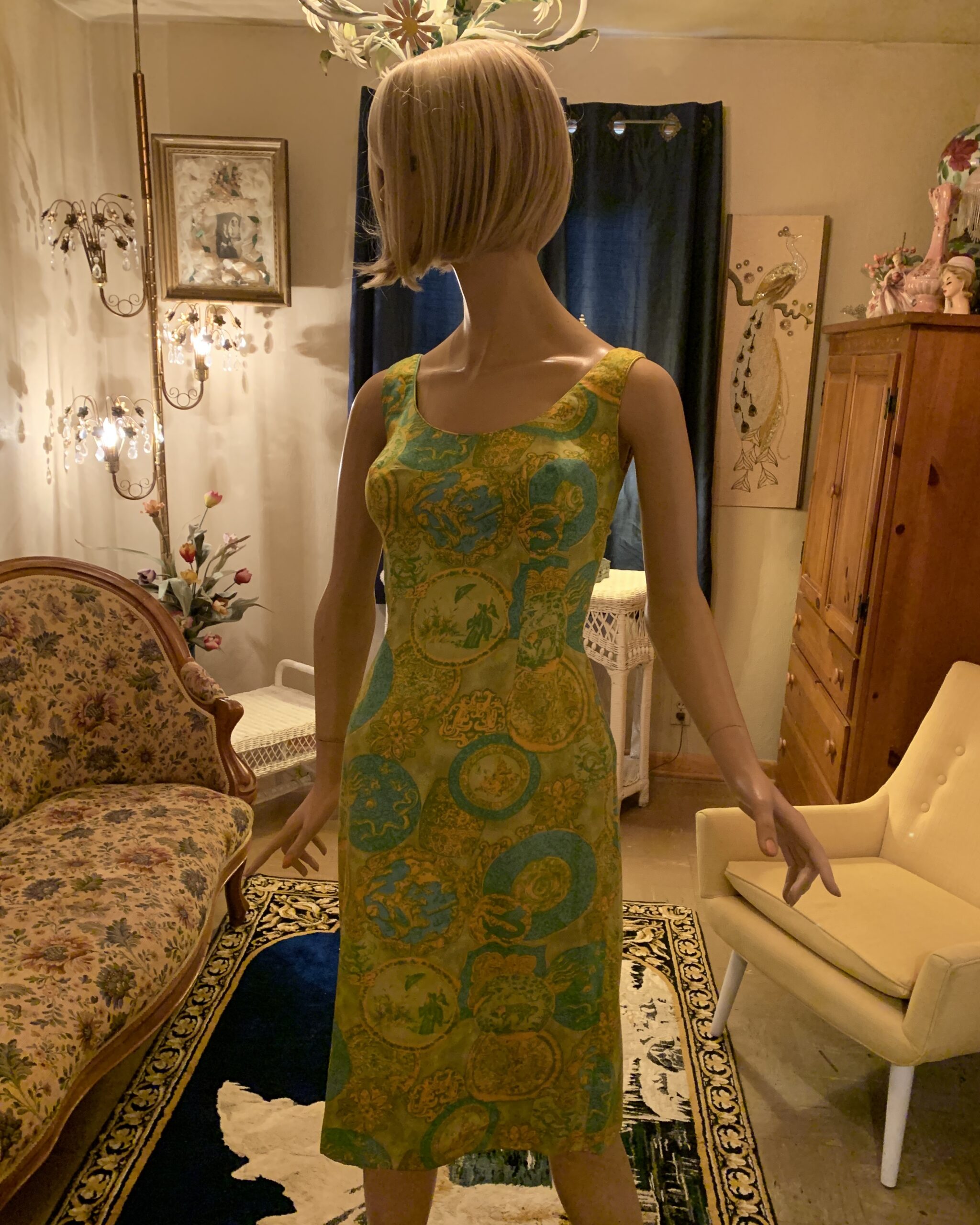 Late 1970s Dynasty sleeveless sheath dress in chartreuse and turquoise novelty print featuring scenic medallions, photographed in the salon of Revolving Vintage Closet.