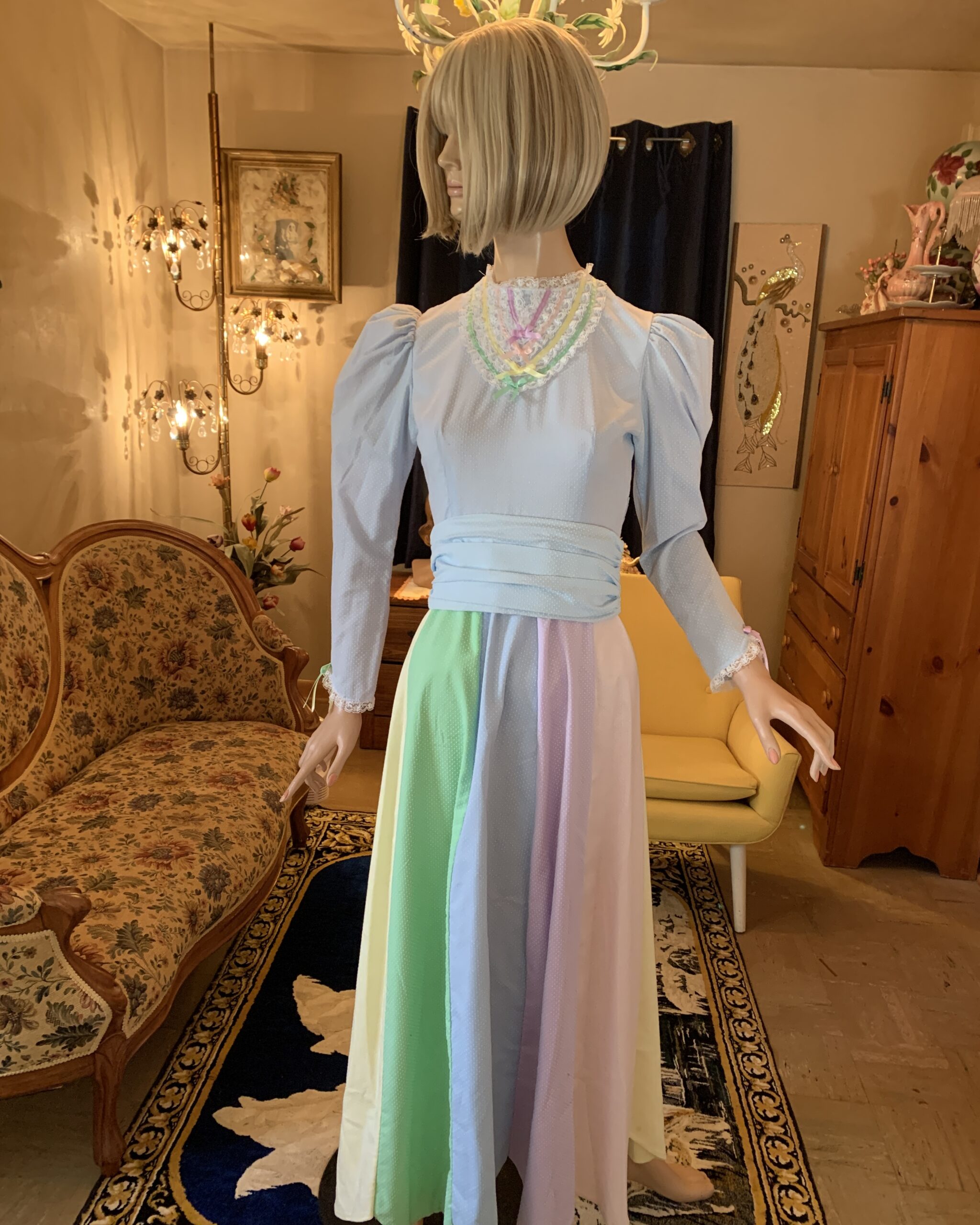 Vintage handmade prairie dress in soft pastel shades of blue, pink, green, and yellow with lace-trimmed neckline and cuffs.