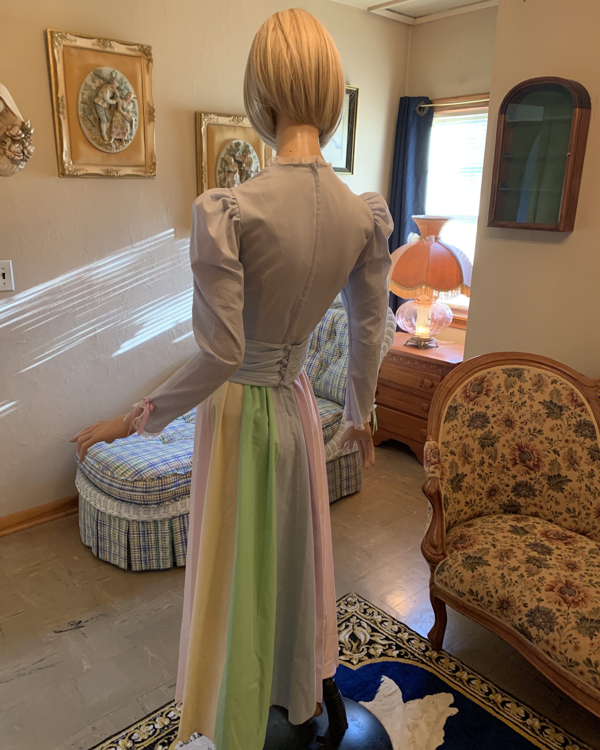 Back view of a handmade pastel prairie dress featuring a wrapped waistband, button closure, and flowing pastel panel skirt.
