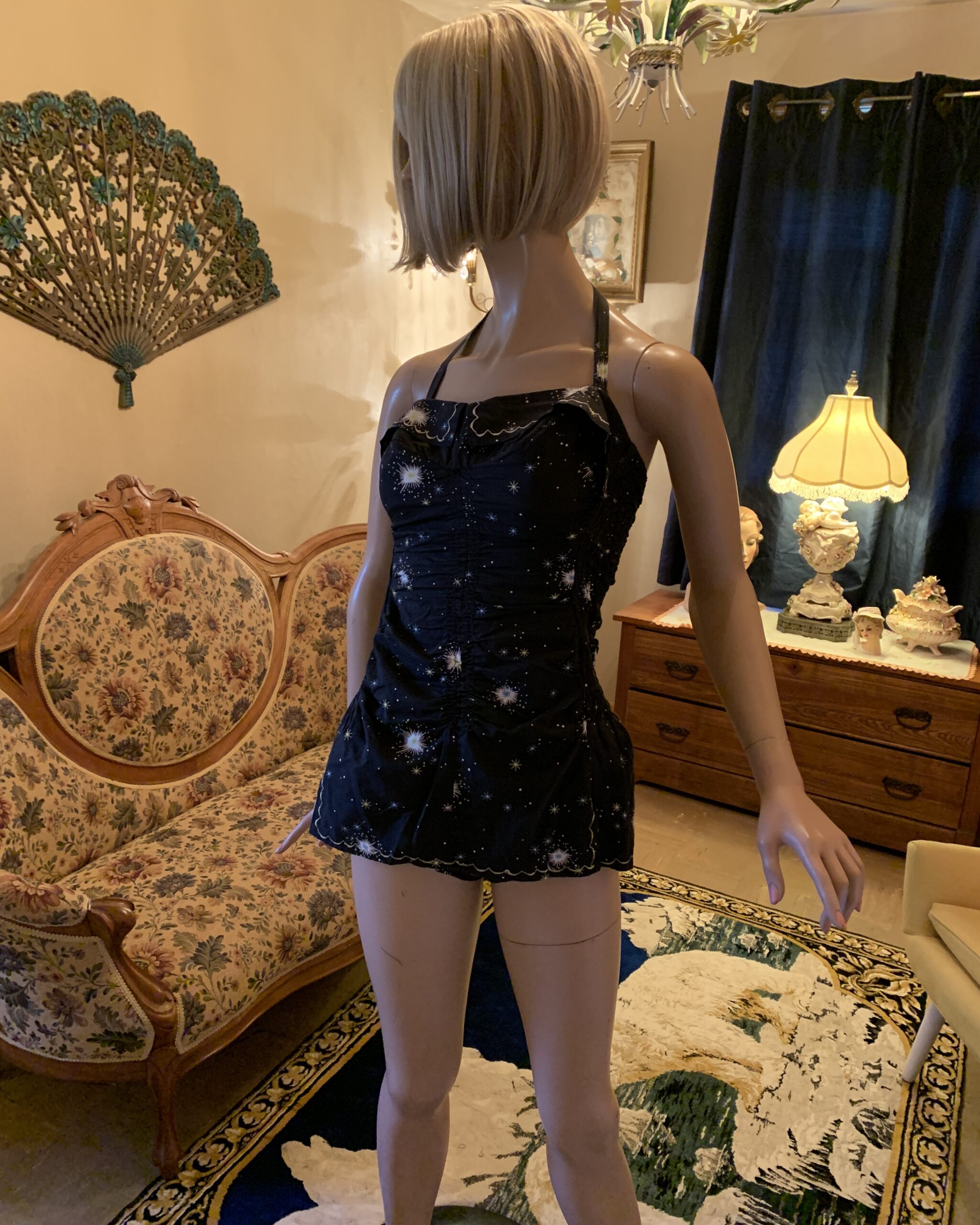Vintage Sea Nymph black halter swimsuit with celestial starburst print displayed on a mannequin in the salon.