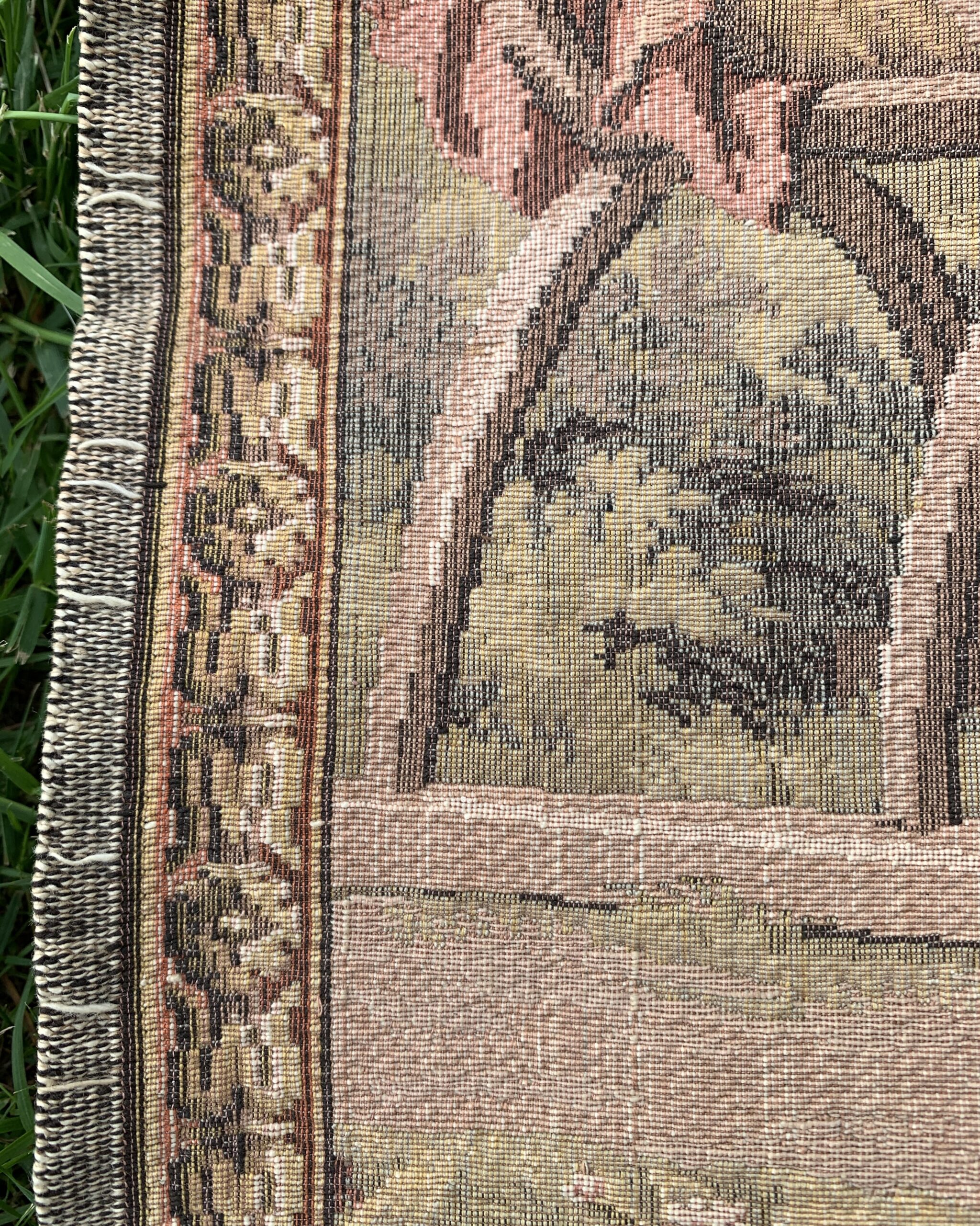 Close-up showing the decorative floral border and woven textile construction of a pastoral tapestry.