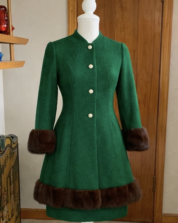 Vintage Lilli Ann green wool skirt suit with brown mink trim and pearl-style buttons displayed on mannequin.