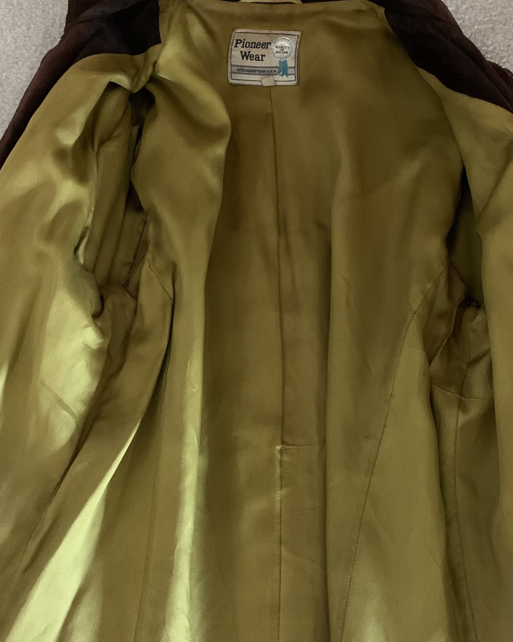 Interior of vintage Pioneer Wear suede fringe jacket with original satin lining and maker’s label.