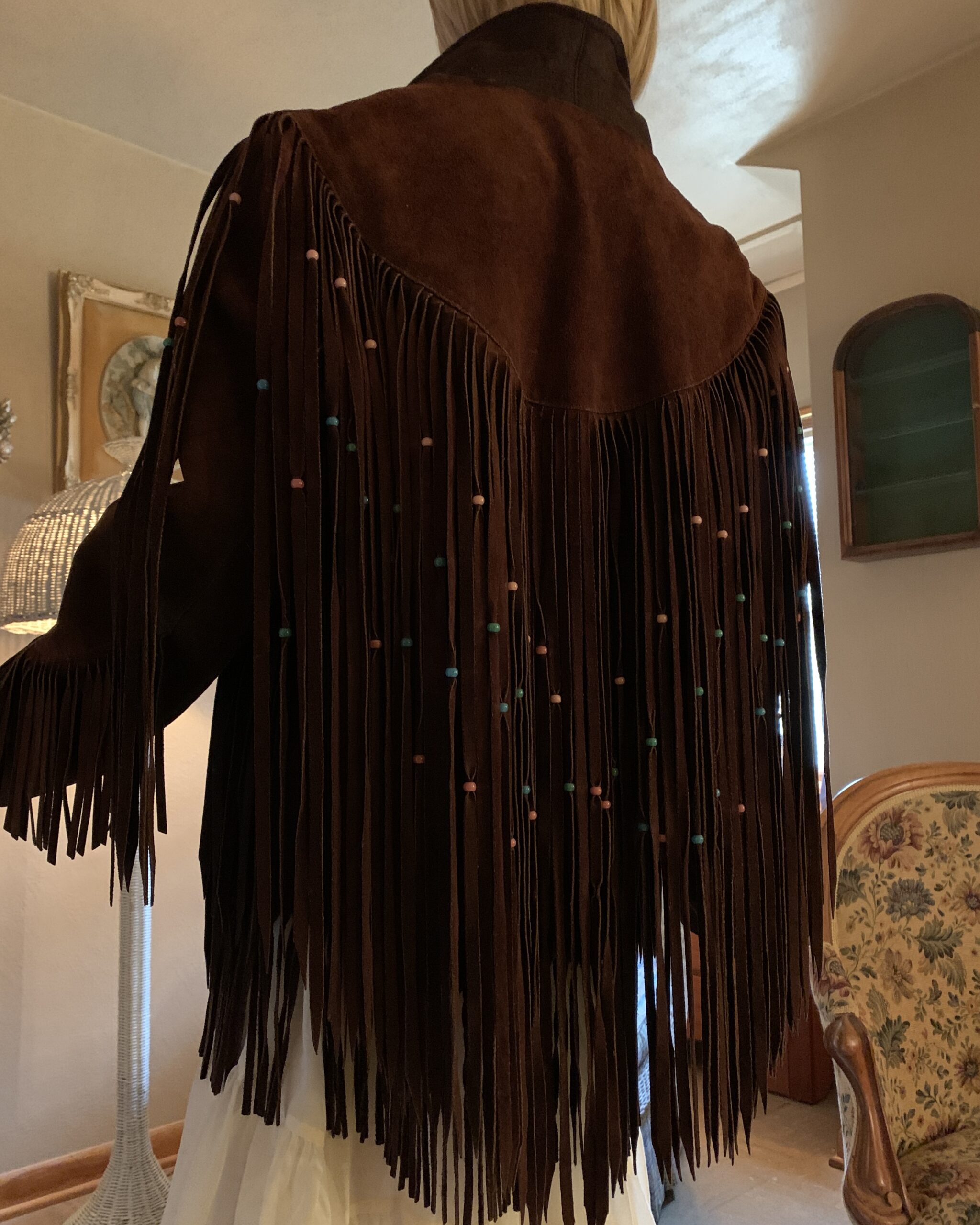 Close-up of the back yoke showing long chocolate brown suede fringe accented with turquoise and pink beads.