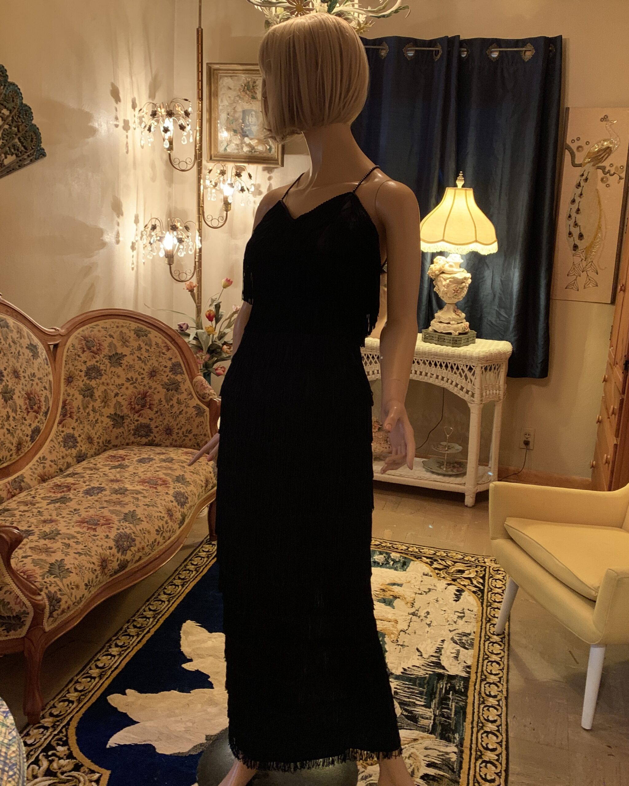 Three-quarter view of vintage Roberta black fringe evening dress with rhinestone shoulder straps.