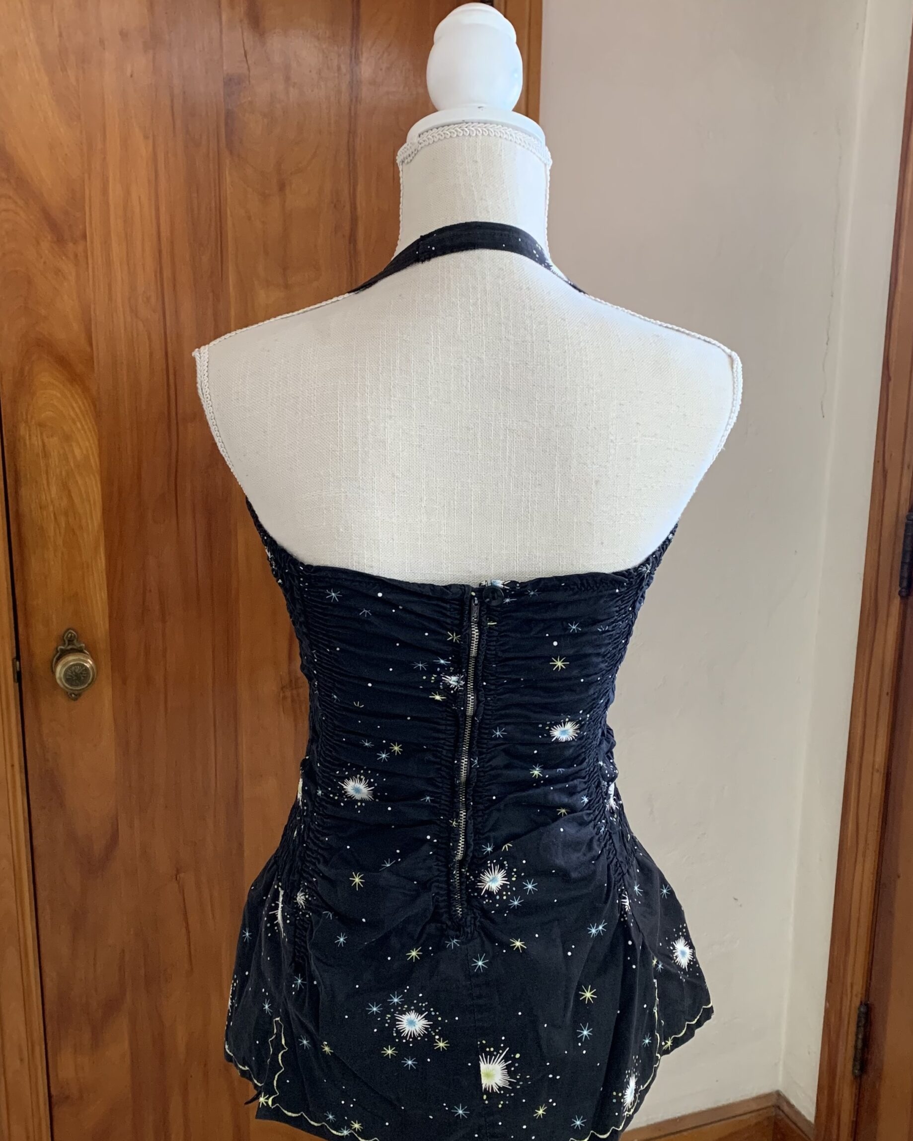 Back view of vintage black atomic print swimsuit with halter strap and metal zipper closure.