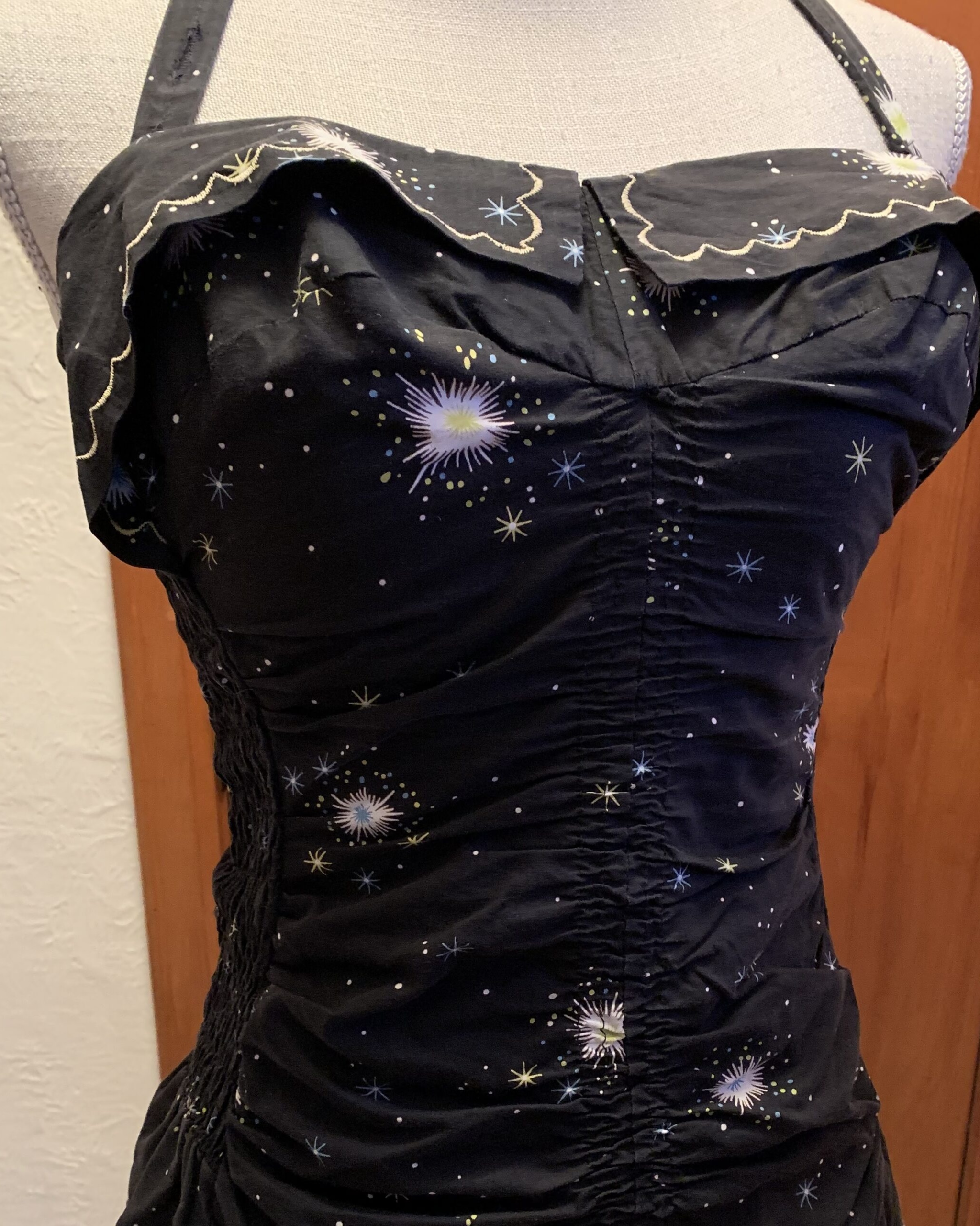 Black mid-century Sea Nymph swimsuit with celestial atomic starburst print and ruched fitted bodice displayed on mannequin.