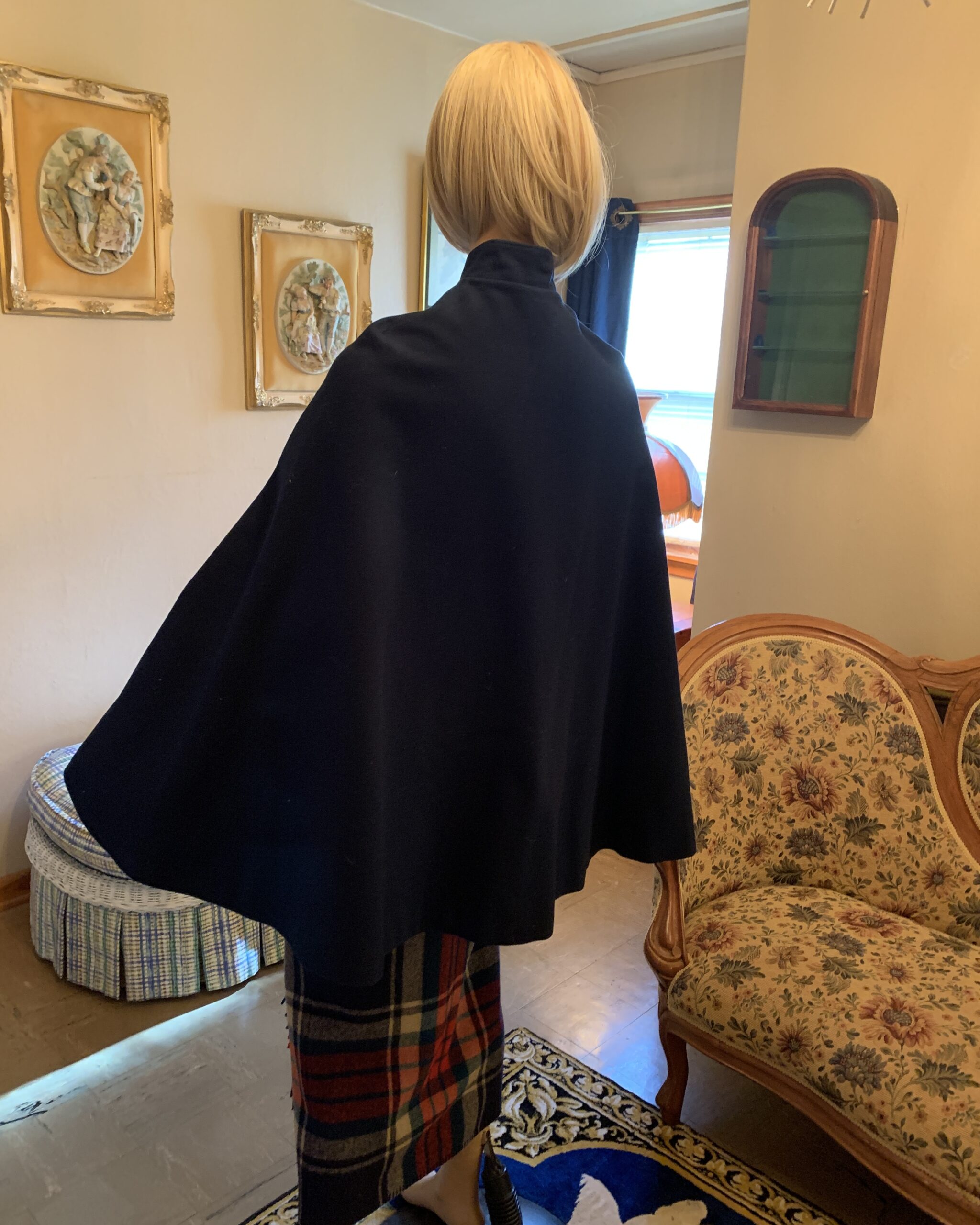 Close-up of embroidered collar detail on a vintage navy blue wool nurses cape with decorative button closures.