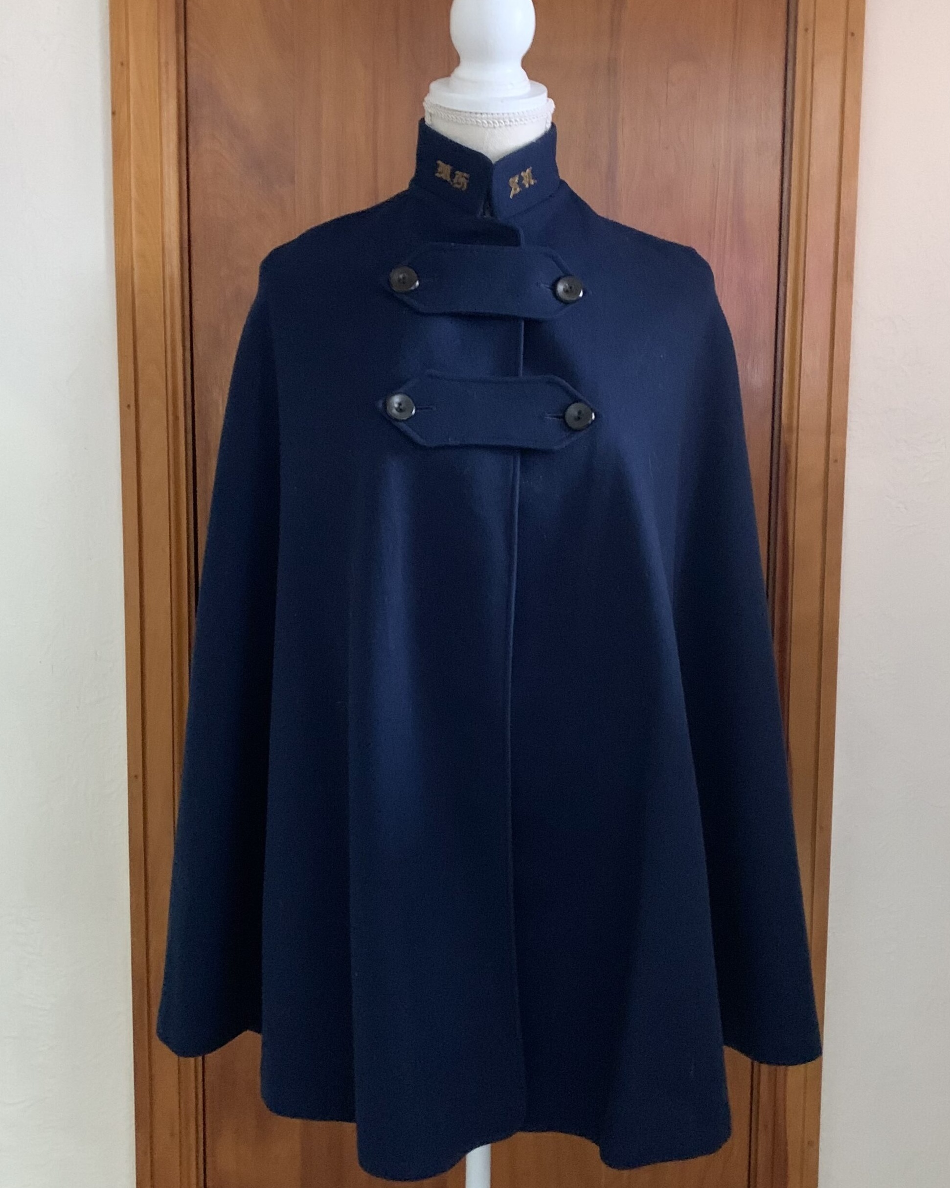 Vintage navy wool cape with military-style collar detailing displayed on mannequin.